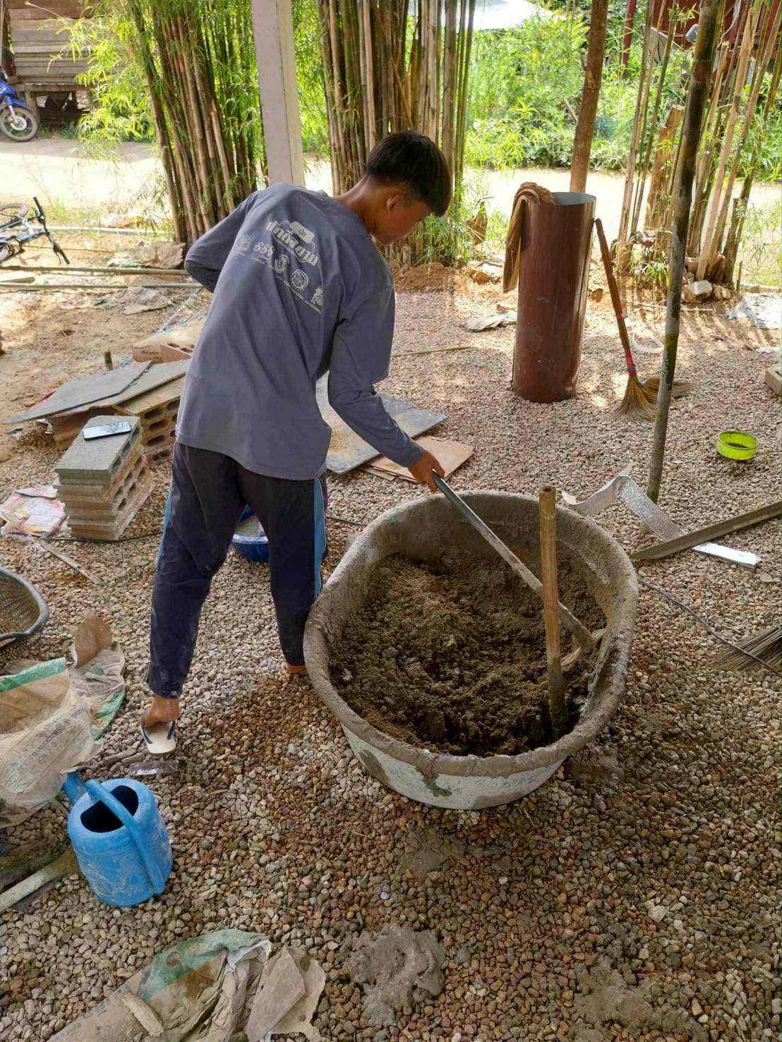 Youth mixing cement with water to prepare for plastering.