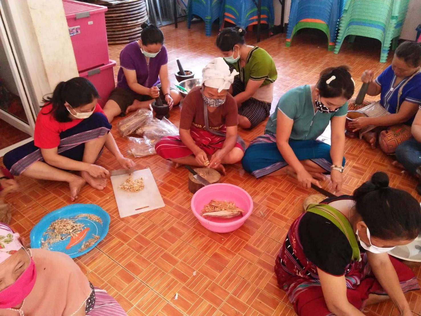 Youth and parents make galangal chili paste and salted fish.