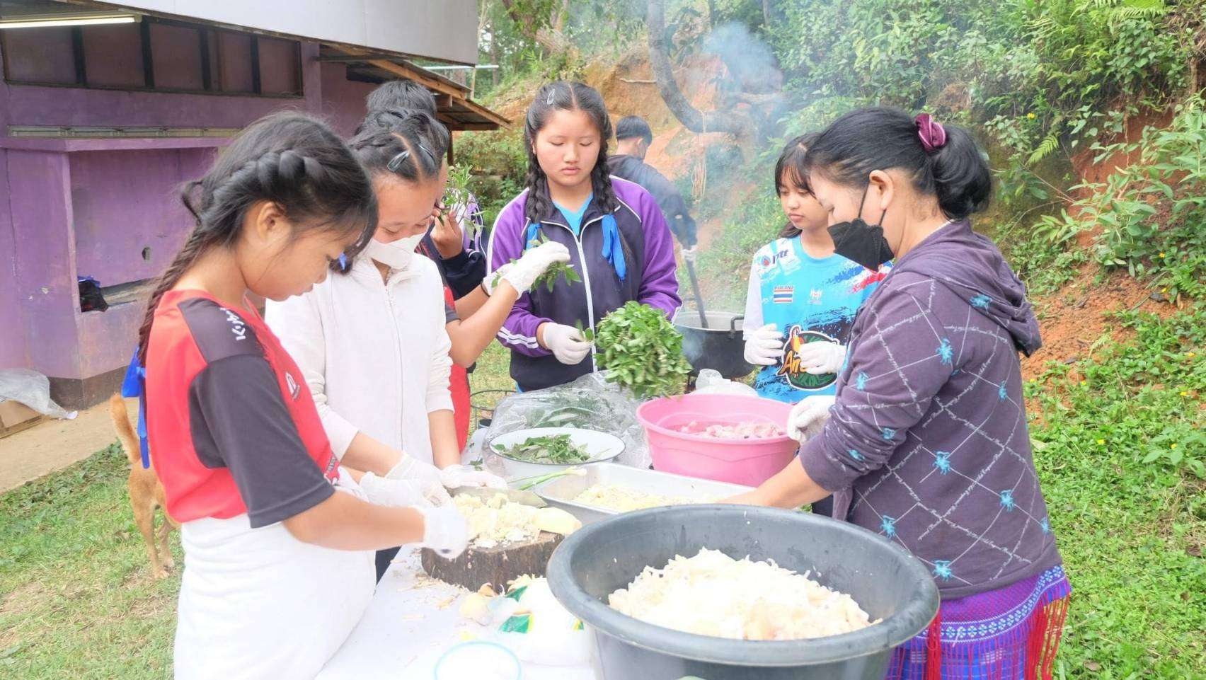 Young people practice banana chip making skills from instructors.