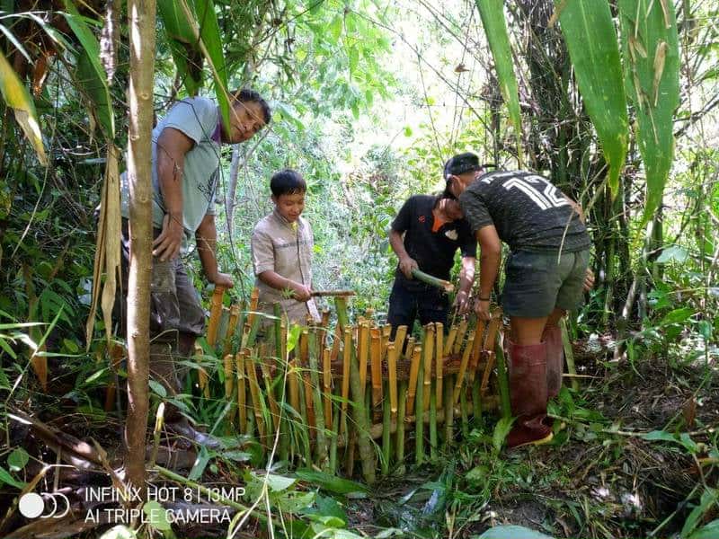 Children and parents help build a water barrier.