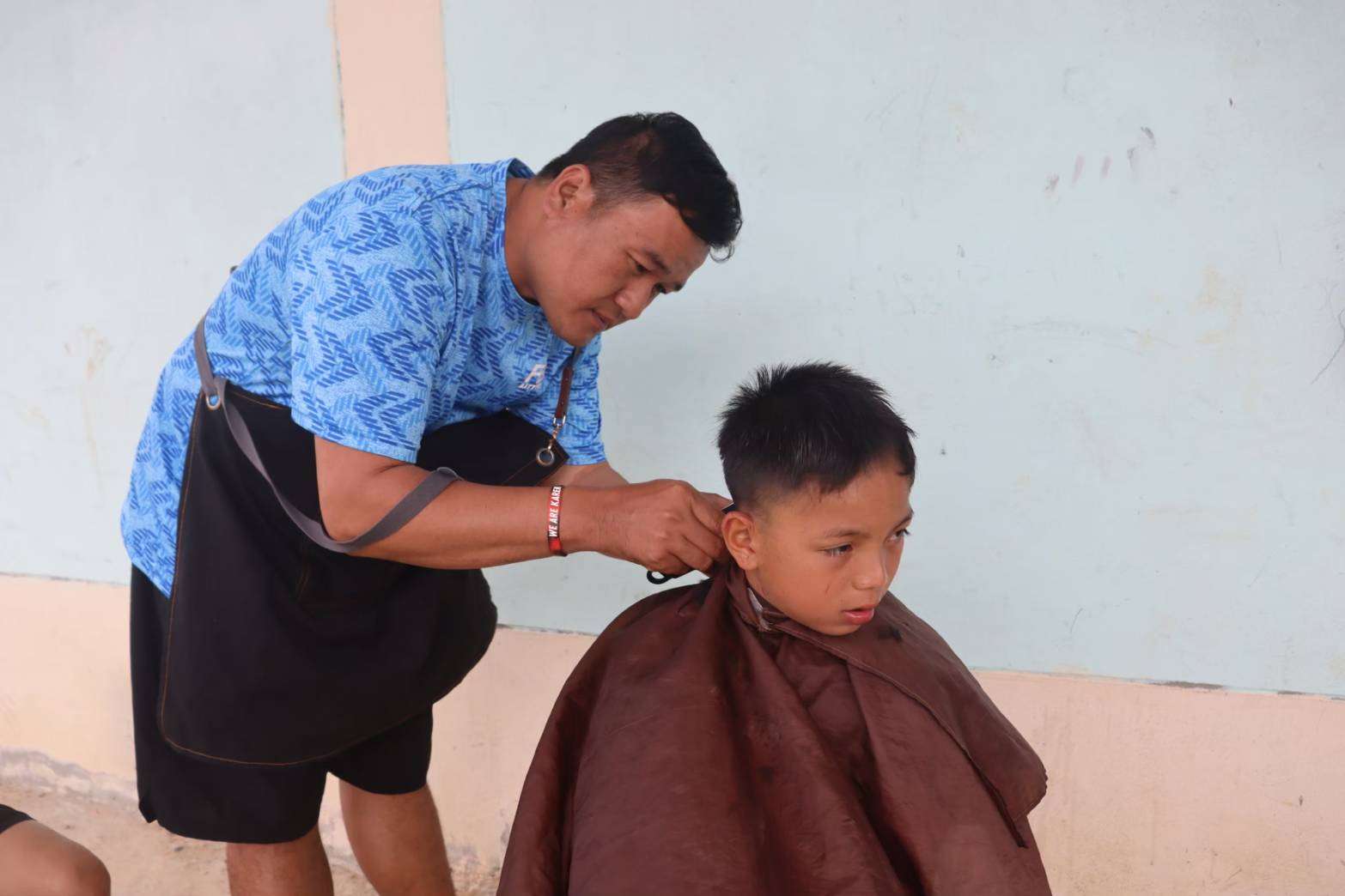 The instructor teaching haircutting skills to the children.