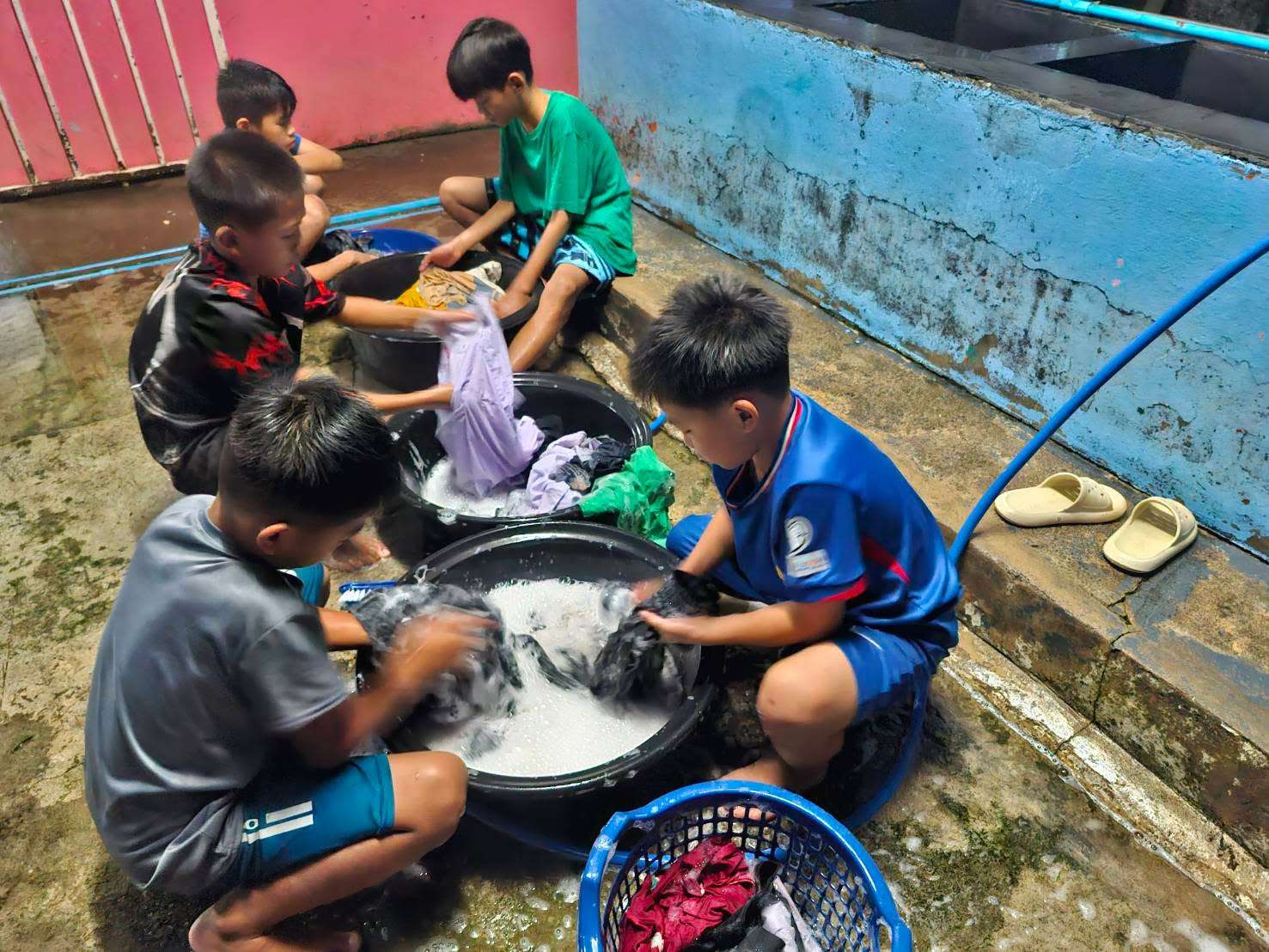 The boy is washing clothes by hand.