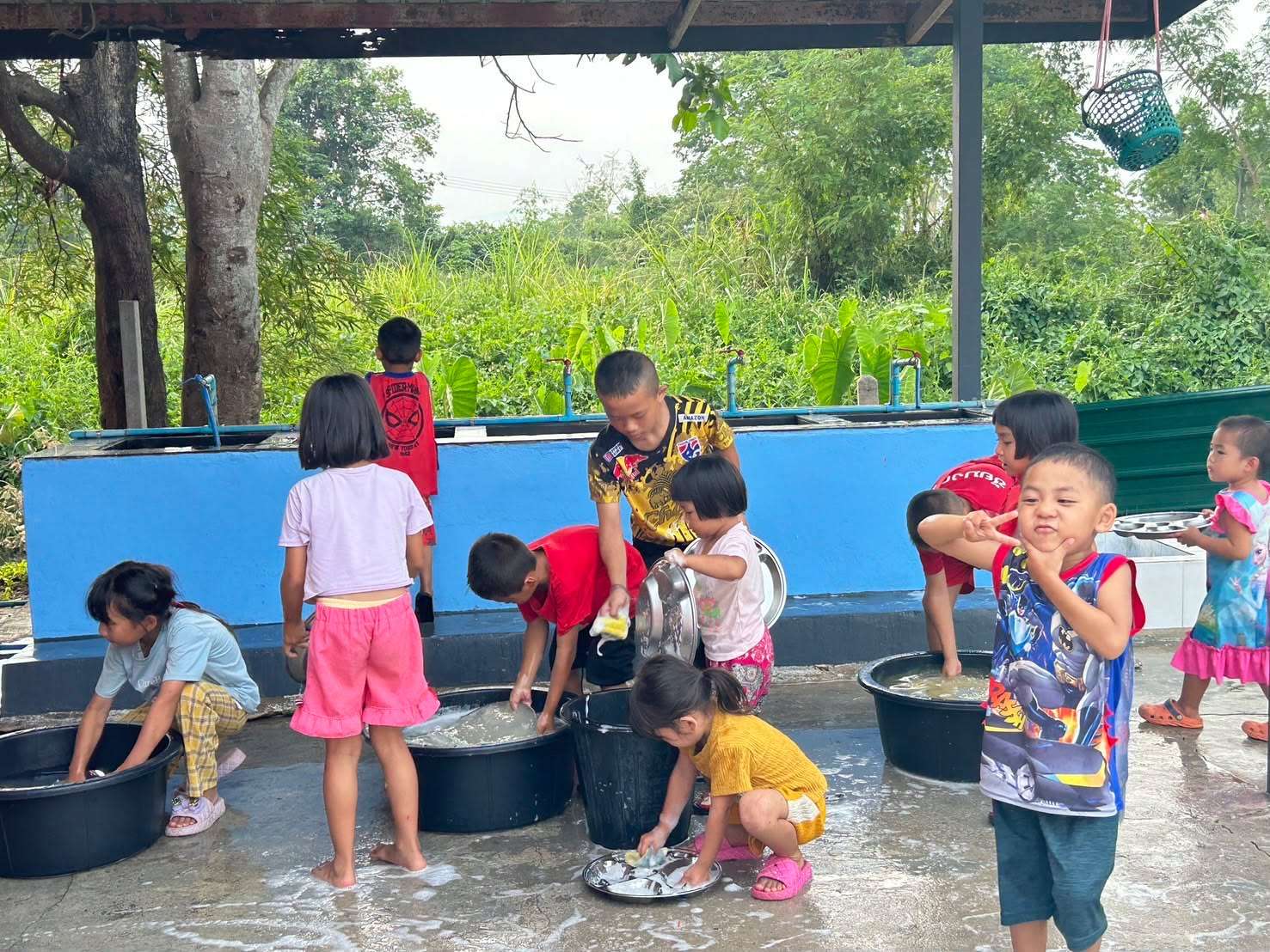 The children are washing their trays after finishing their meal.