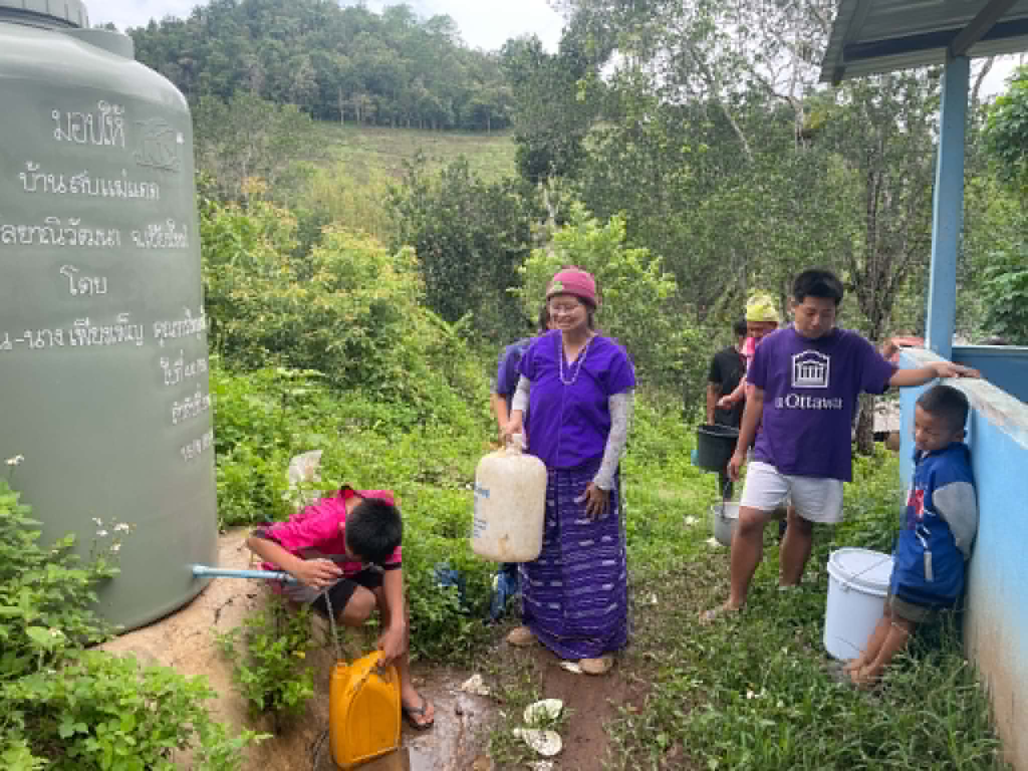 Children and their parents waited in line to fill the community water tank for their use.