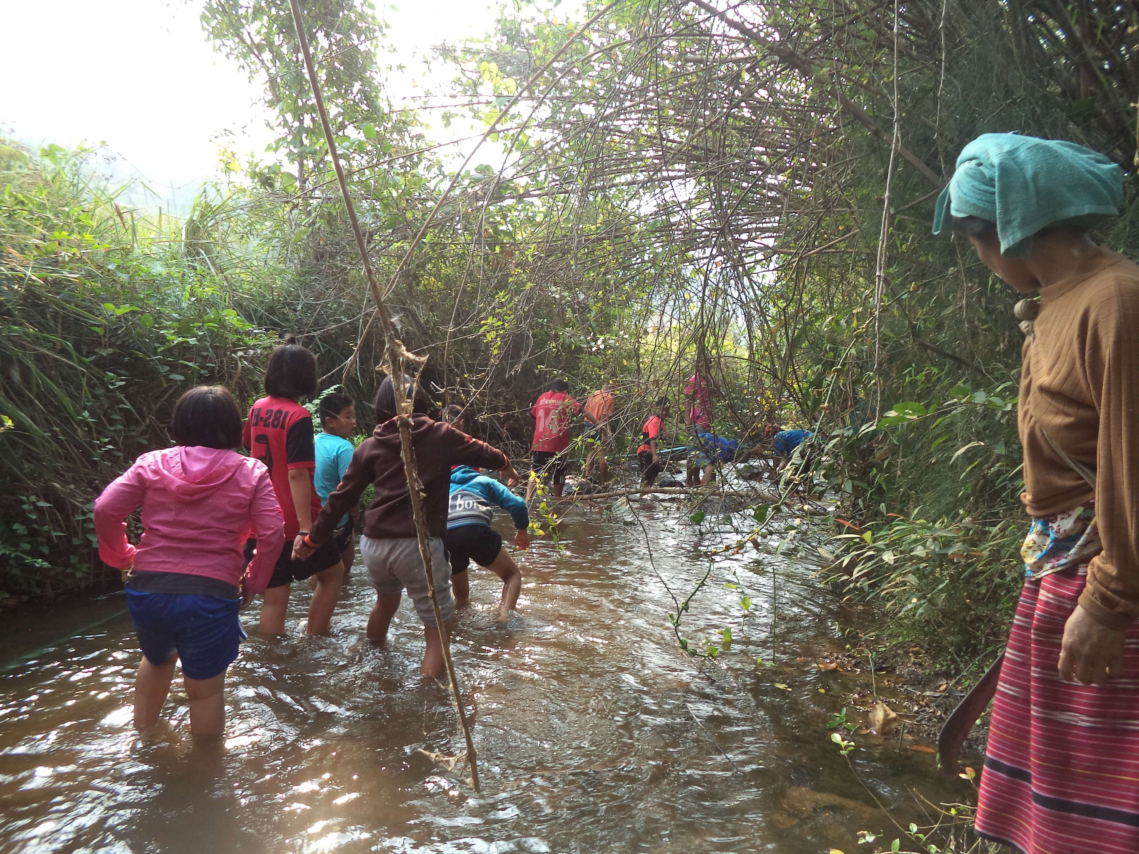 Children learn about the environment and explore and collect trash along the river.