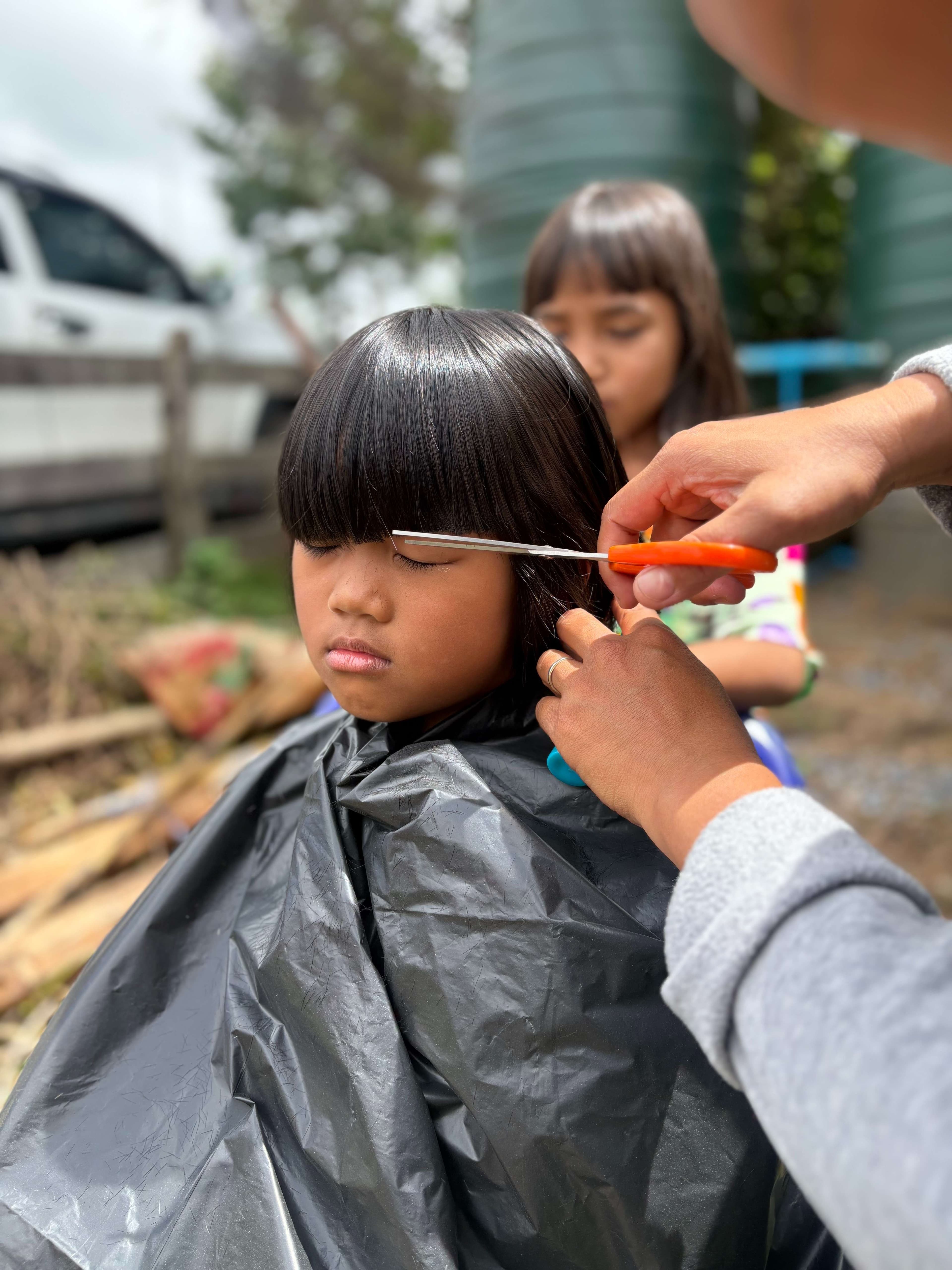 Using a plastic garbage bag as a cape while getting a haircut.