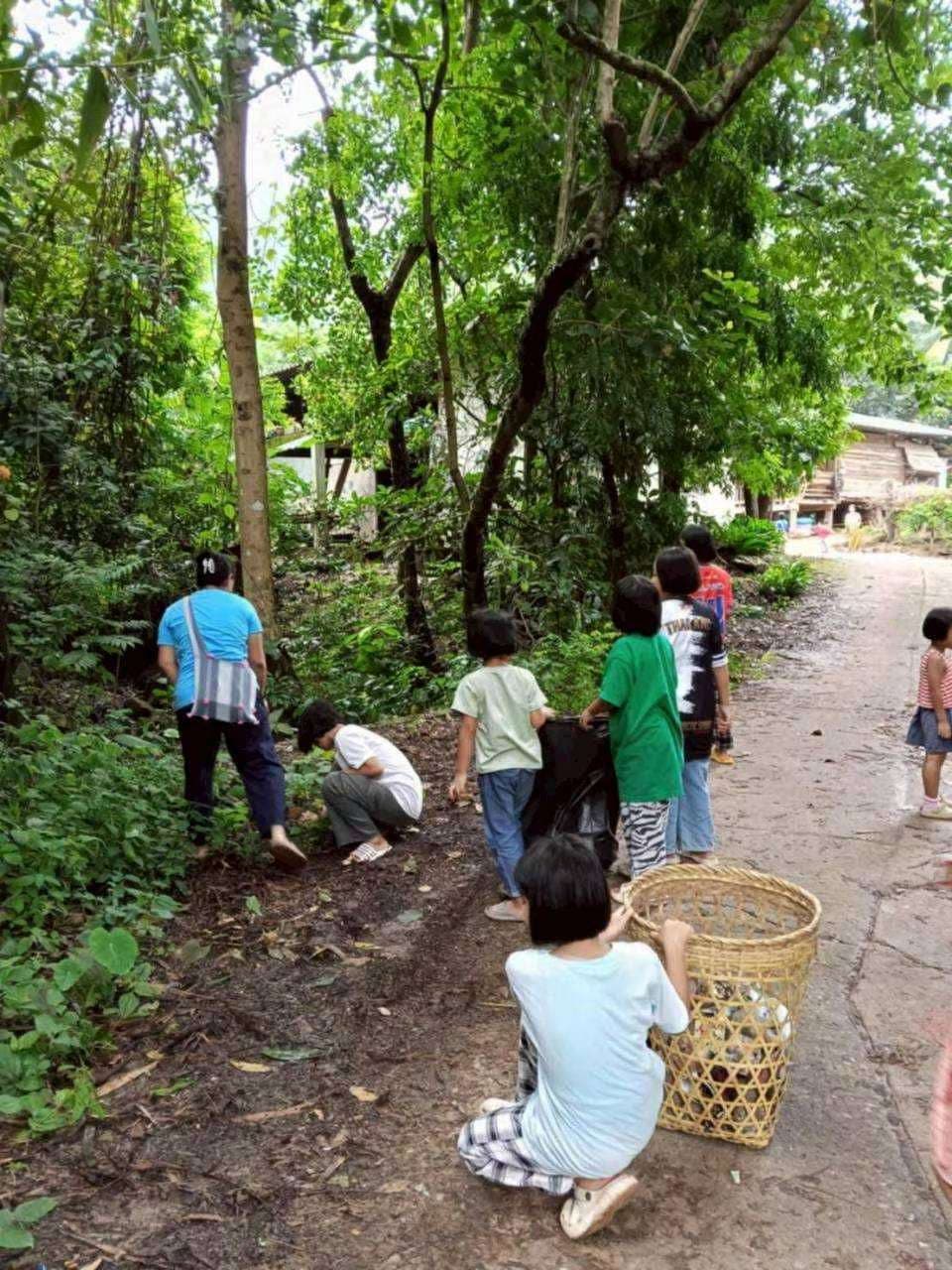 The children are collecting trash along the stream in the village.