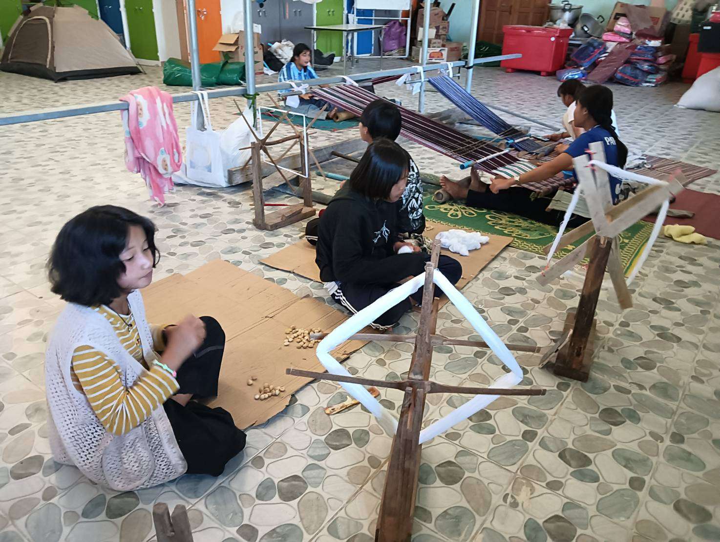 Children learn how to prepare cotton before weaving.