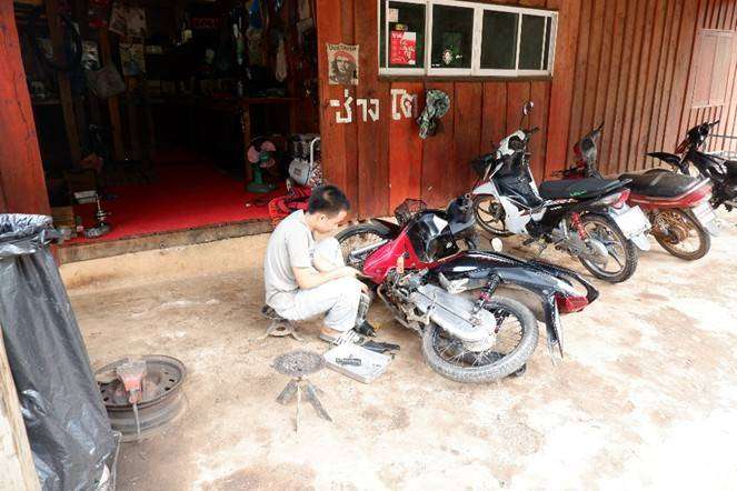 The young people are changing a motorcycle tire.