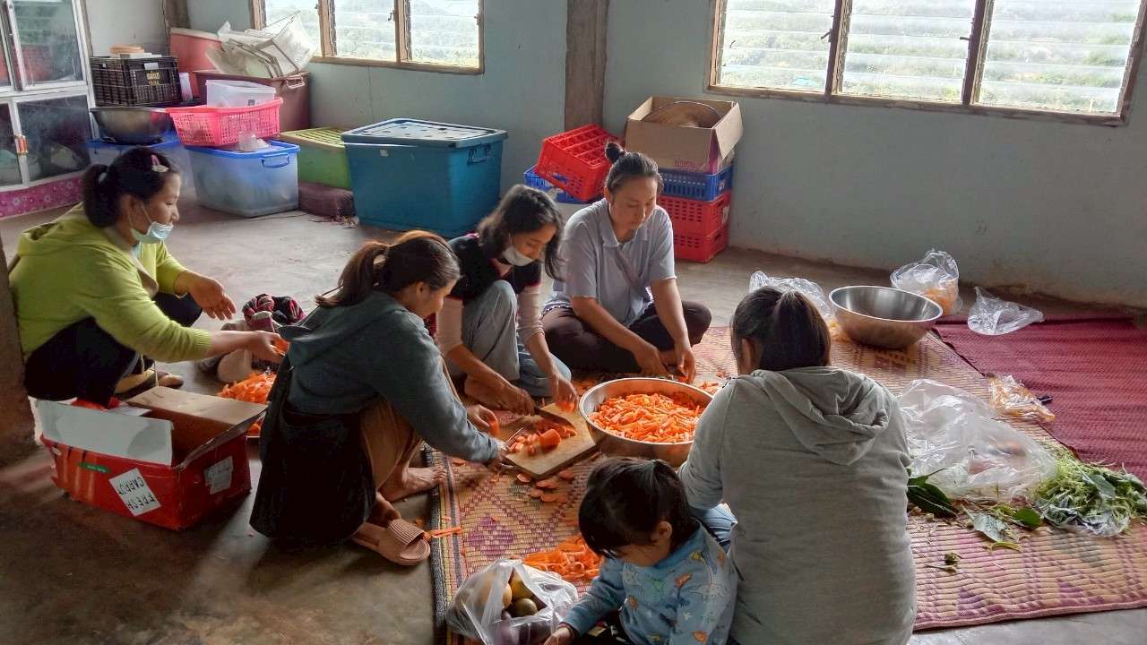 Youth sitting on the floor, diligently preparing food together.