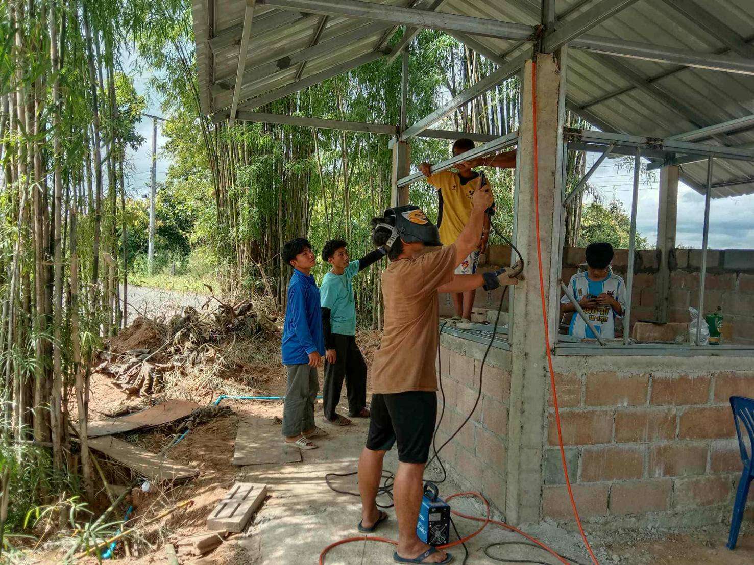 Youth constructing a frame for cement building.