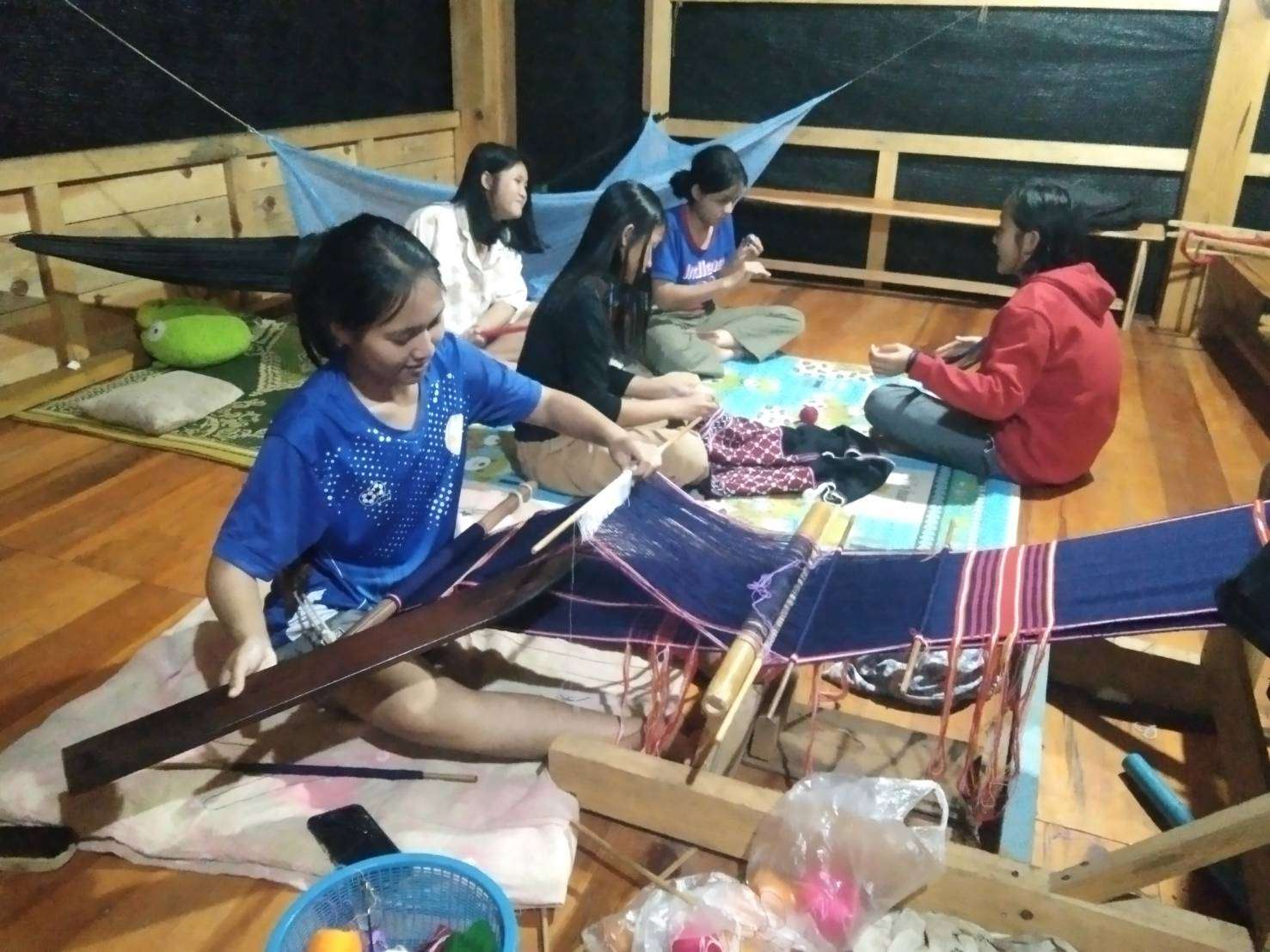 A girl learns to weave patterns on cloth.