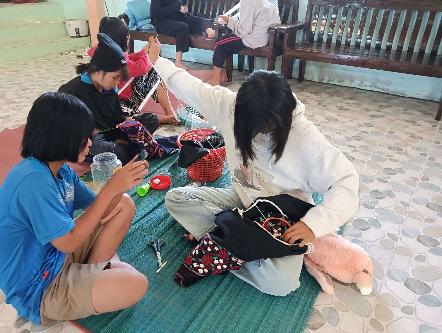 Girls proudly embroider the finished tribal clothing, bringing cultural threads to life with skill and pride.
