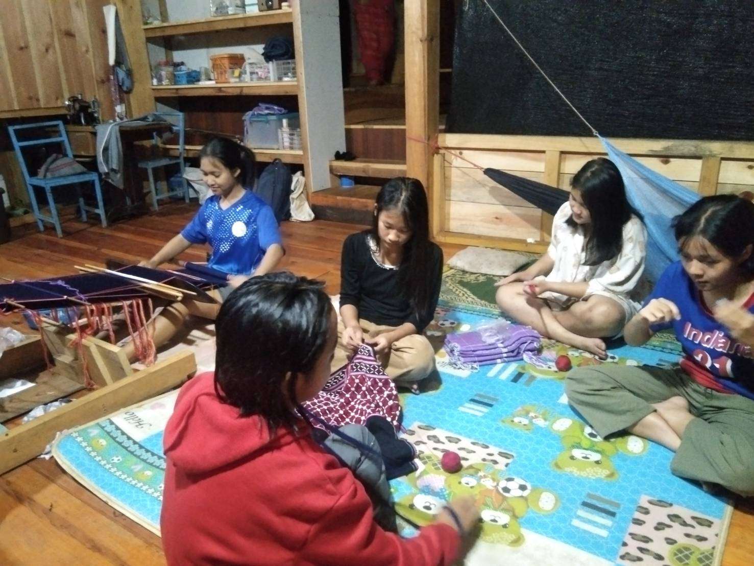 Children gather together to weave, embroider and spin cotton to create unity.