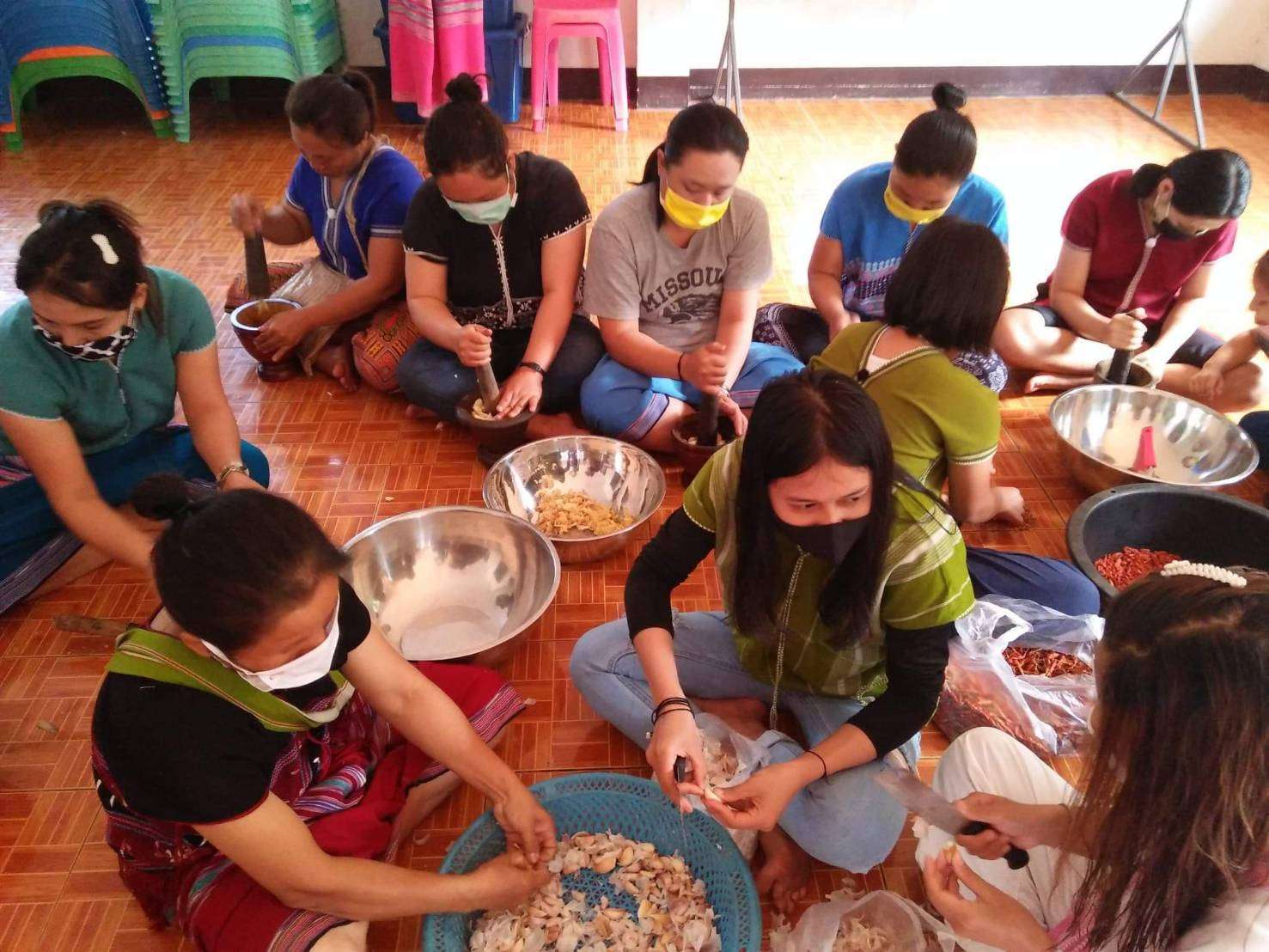 Youth and parents make chili paste with galangal and salted fish.