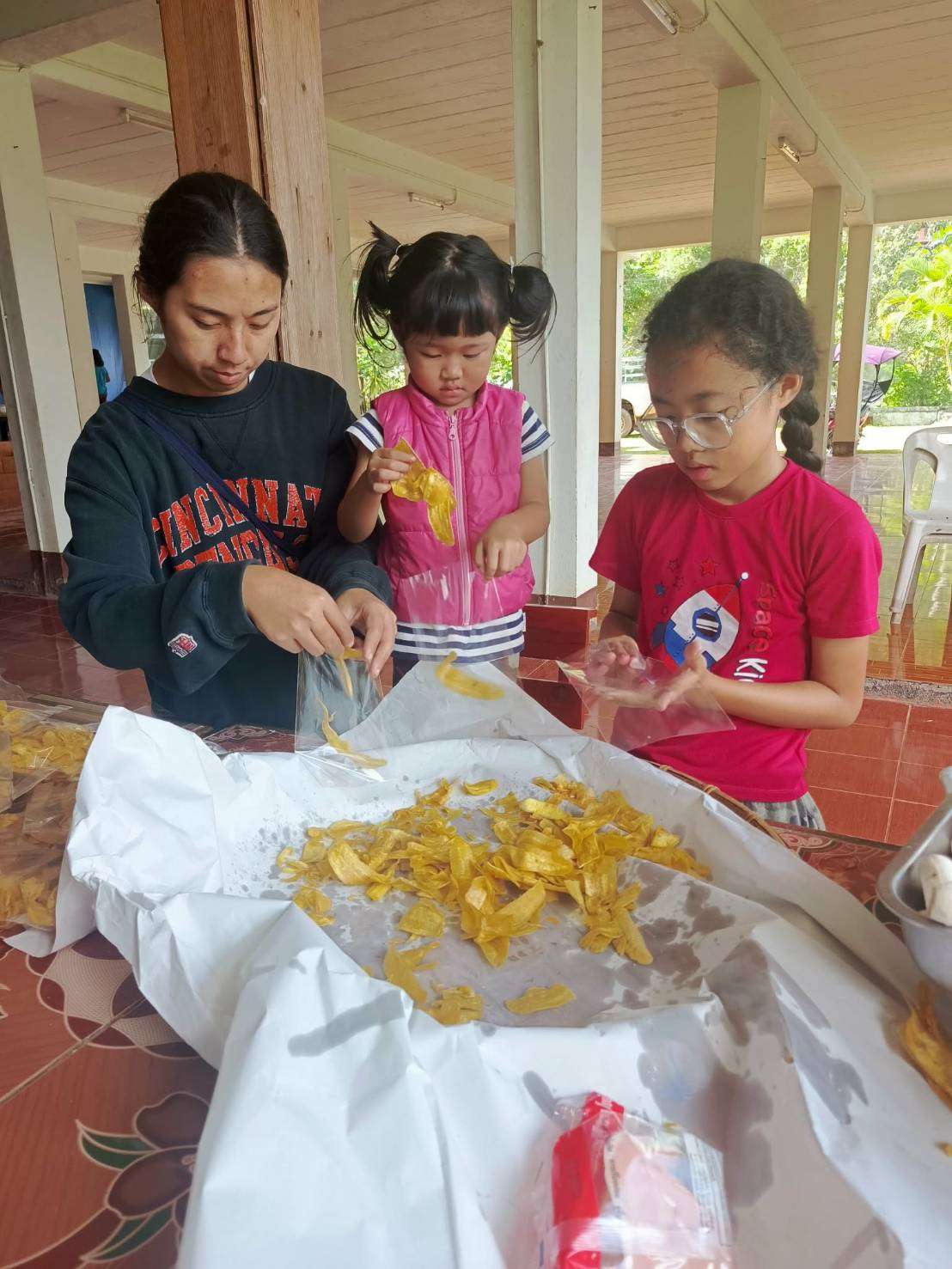 The children learning how to make banana chips.