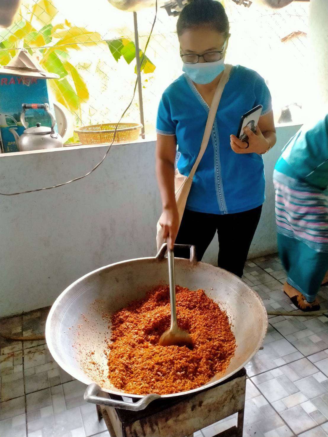 Youth and parents collaboratively making galangal chili paste and salted fish.
