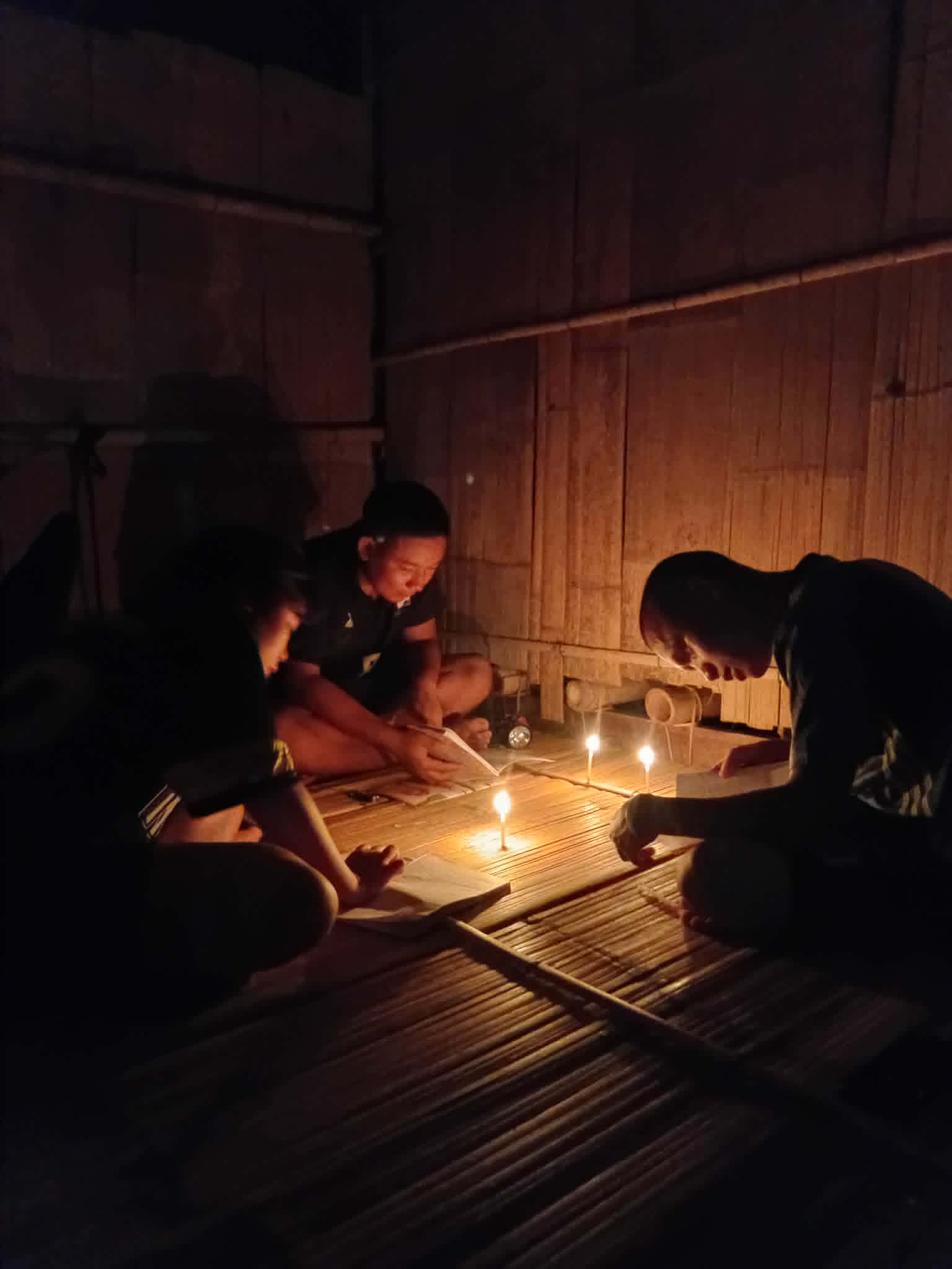 Children rely on dim candlelight to read and study
