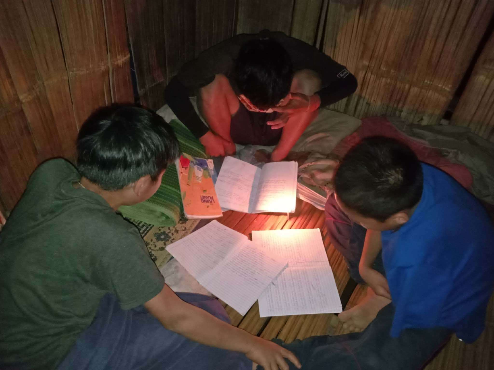 Together in Learning: Children collaborating to finish their homework using torchlight, illuminating their path to knowledge.