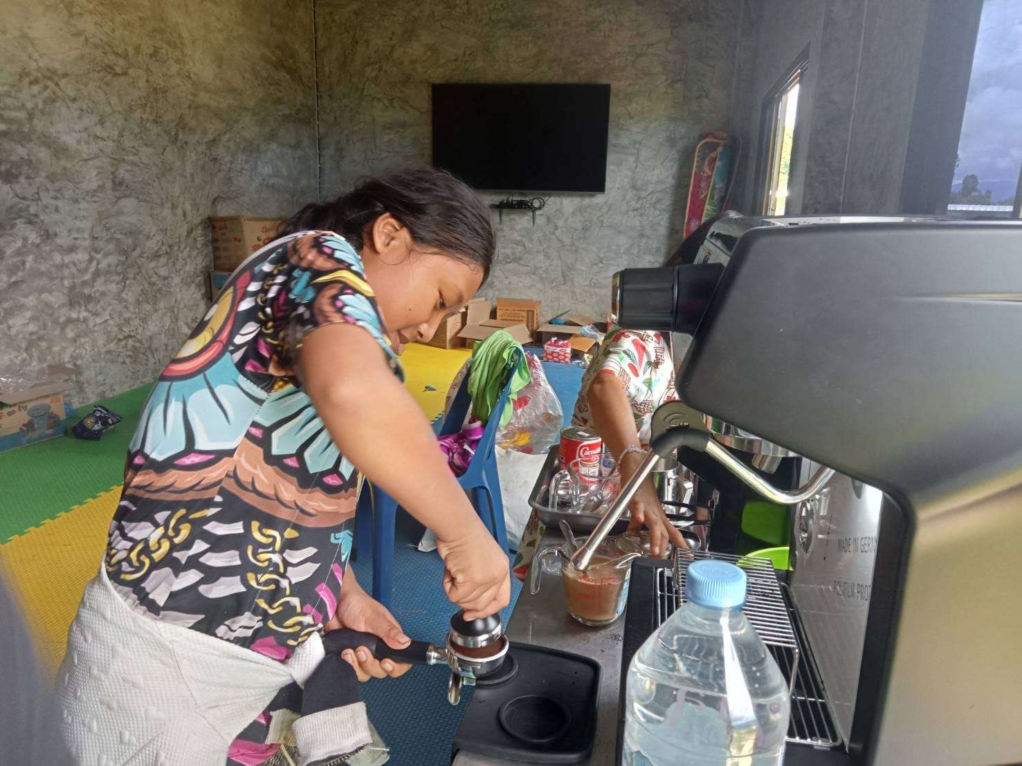 The youngsters are practicing how to use the coffee maker, gaining hands-on experience to enhance their skills and confidence for future opportunities.