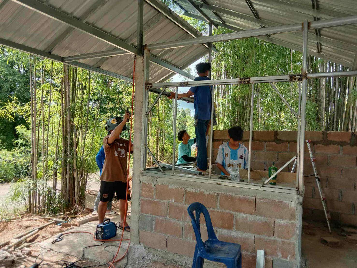 Youth skillfully plastering and welding the frame for construction.