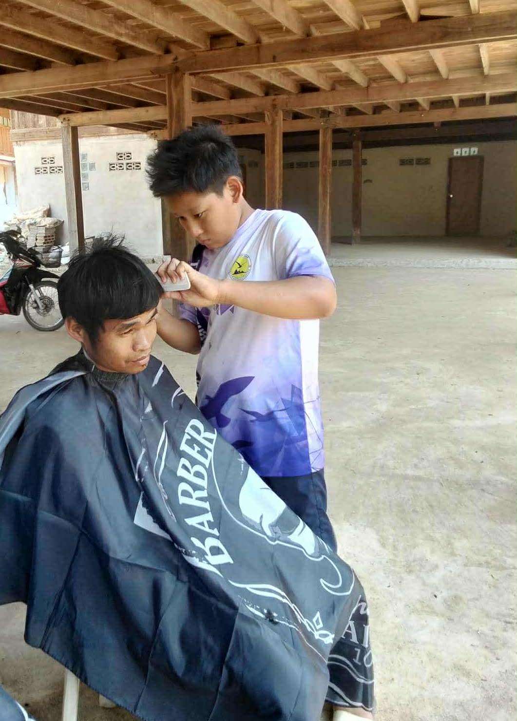 Youths concentrating on their first real haircut after hours of learning in the class