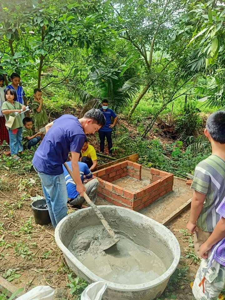Parents and volunteers work together to build the foundation of the incinerator.