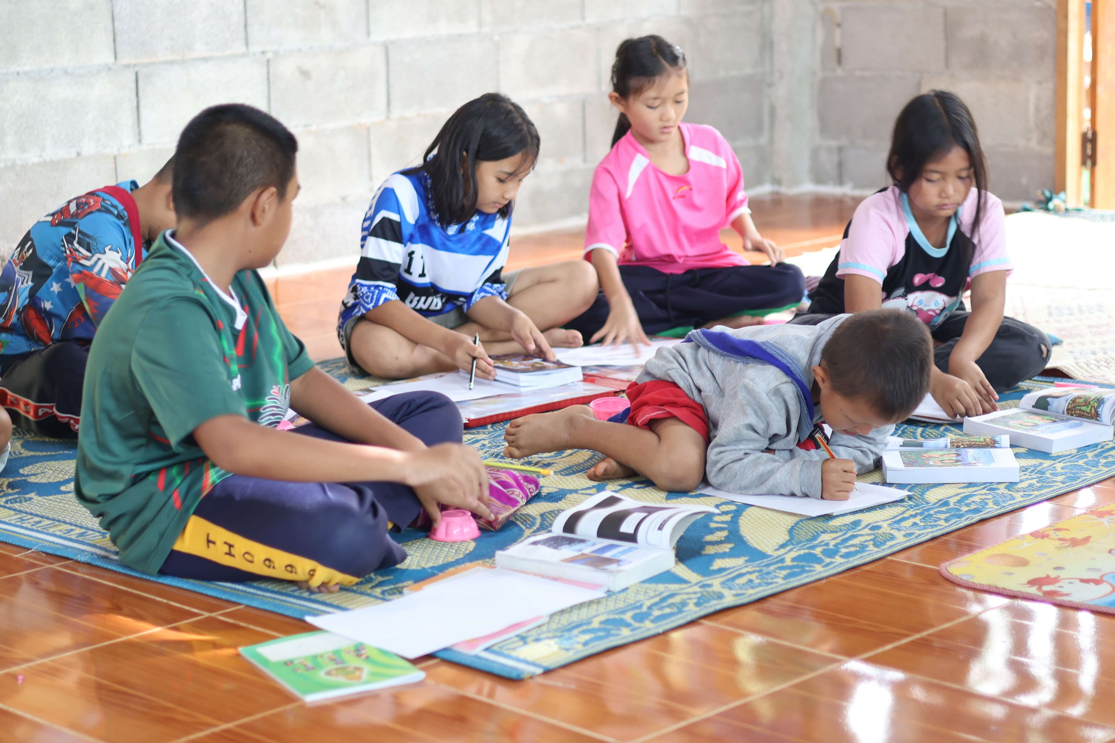 The children sit on the floor to write, which causes them back pain.