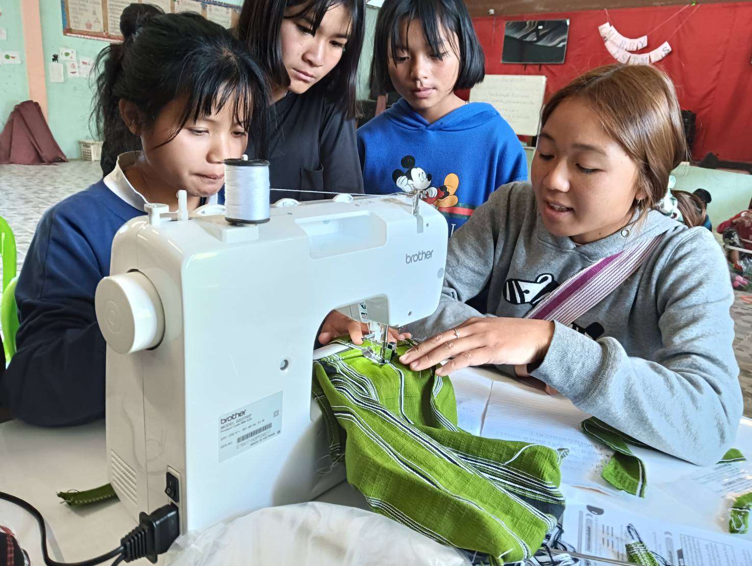 Children learn to master the electric sewing machine, gaining vital skills for their future and empowering their craftsmanship.