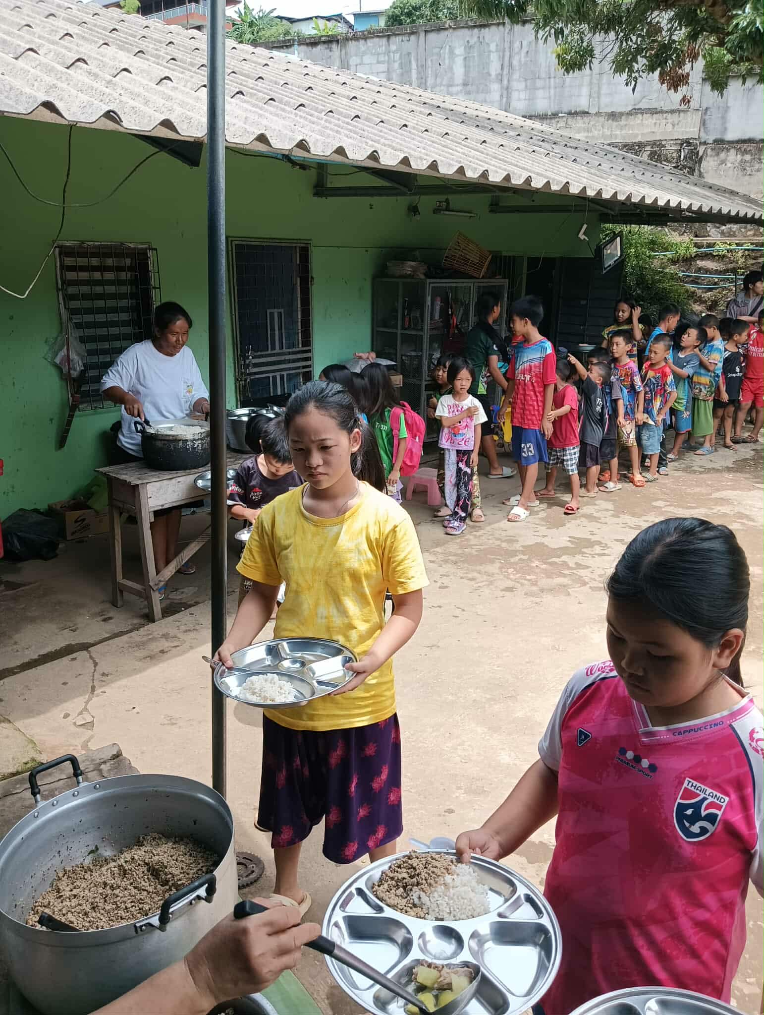 Hope in every line: Our children eagerly serve themselves rice, a step towards a brighter future with the Canteen of Hope.