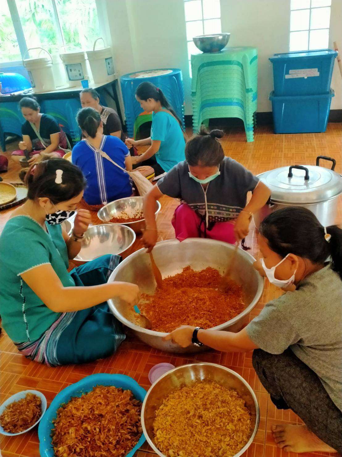 Youth and parents working together to make delicious galangal chili paste and salted fish.