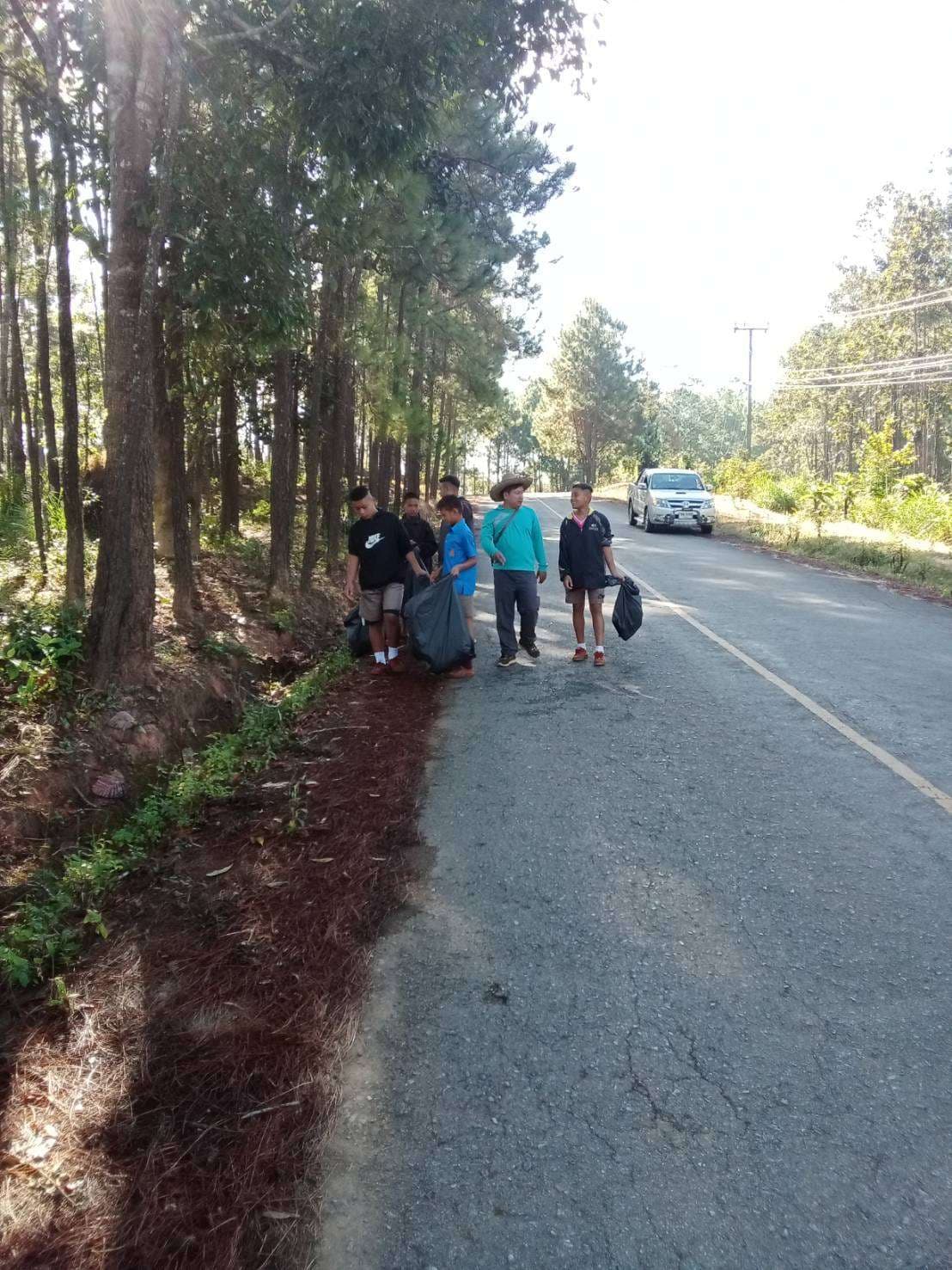 Joining their teachers in collecting trash at school.