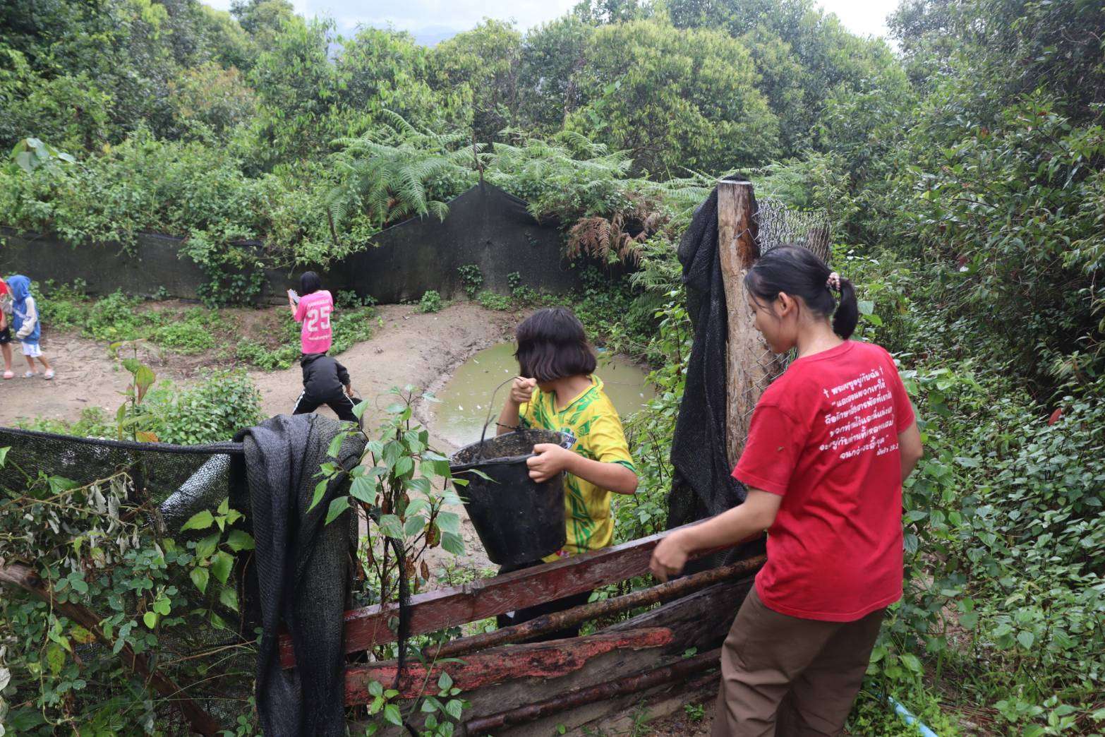 The community using water for bathing and washing clothes, highlighting the community’s access to water for daily needs.