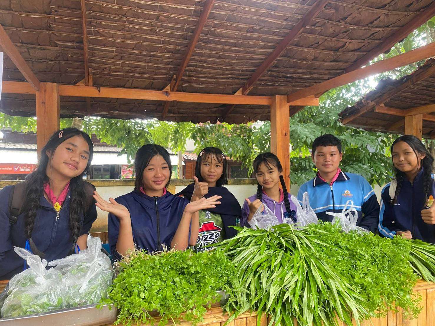 Youth bring excess produce from their vegetable garden to sell to generate income.