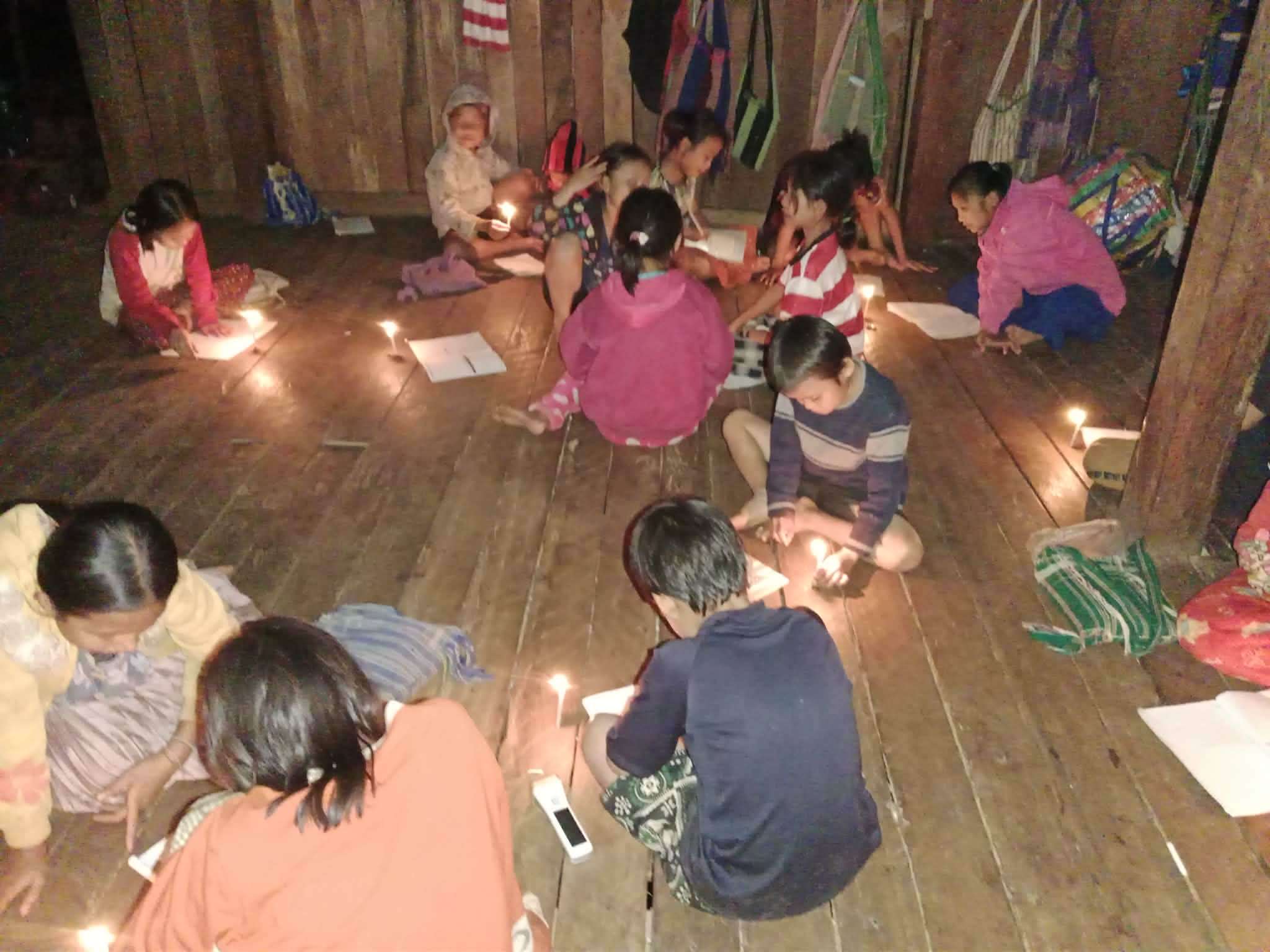 Completing homework under candlelight, showcasing determination and resilience.