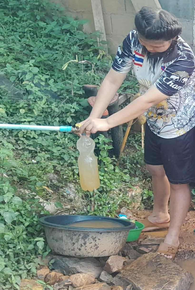 A young girl uses a water bottle to collect murky water from the tap, hoping to get clean water.