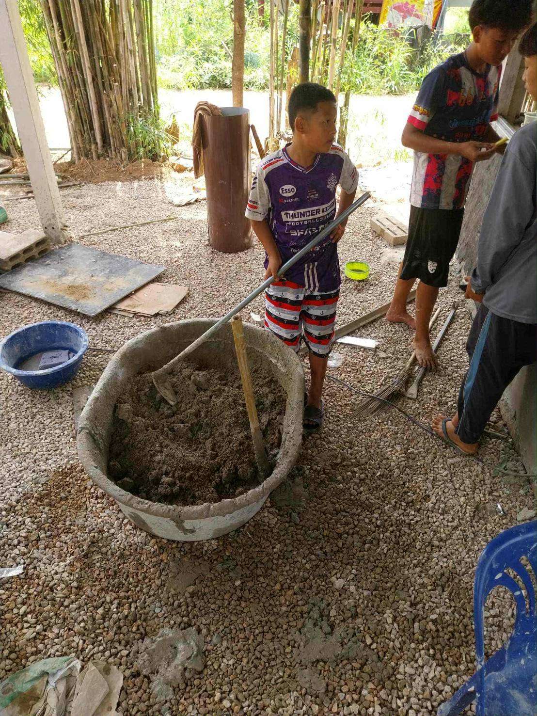 Youth practicing cement mixing for plastering projects.