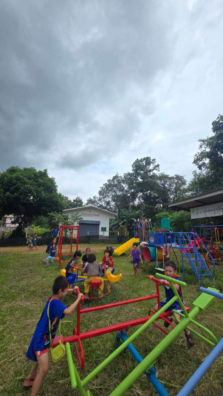 The children eagerly head to the playground before joining the project activities, but dark clouds in the sky suggest that rain may be on the way.