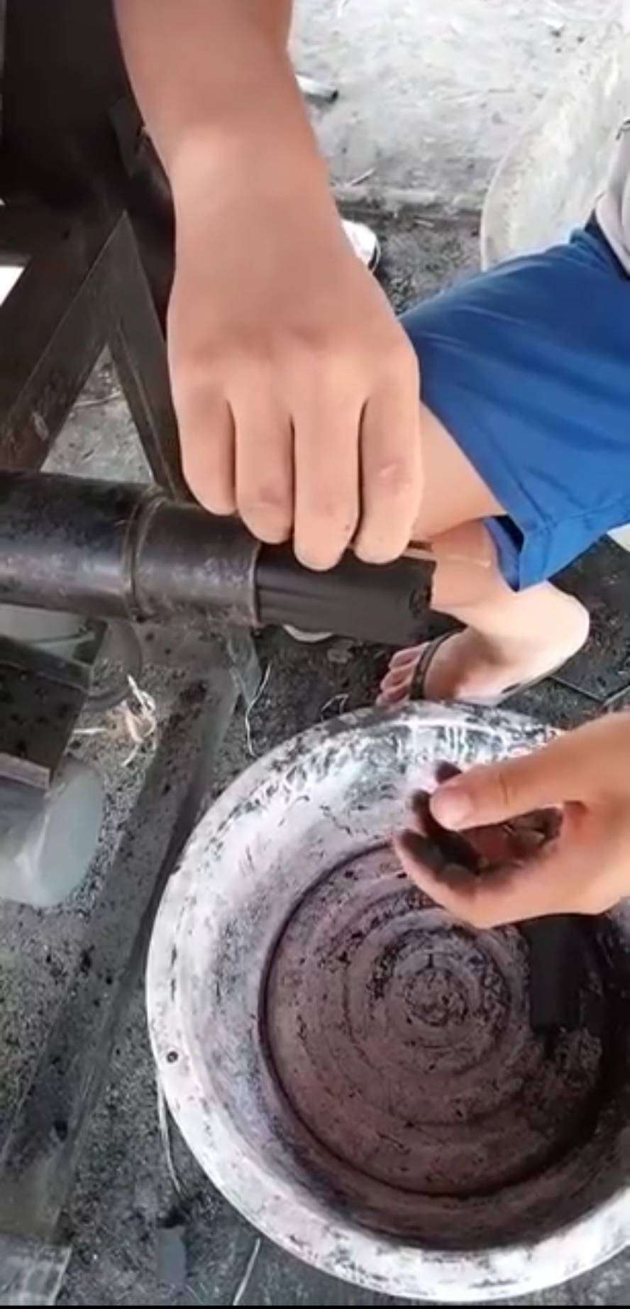 Children await their turn to place the charcoal into the basin, symbolizing community involvement and future generations' connection to sustainable energy practices.