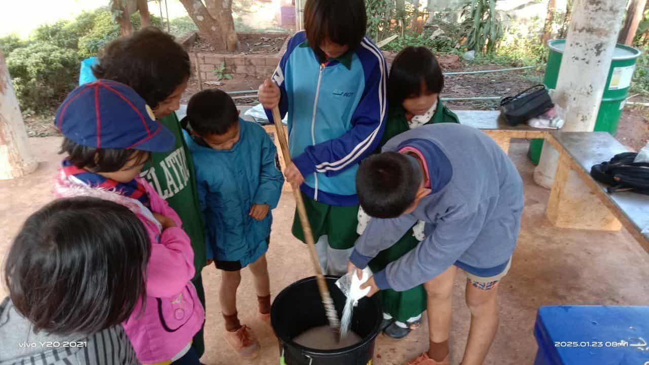The kids helping each other pour dishwashing liquid.