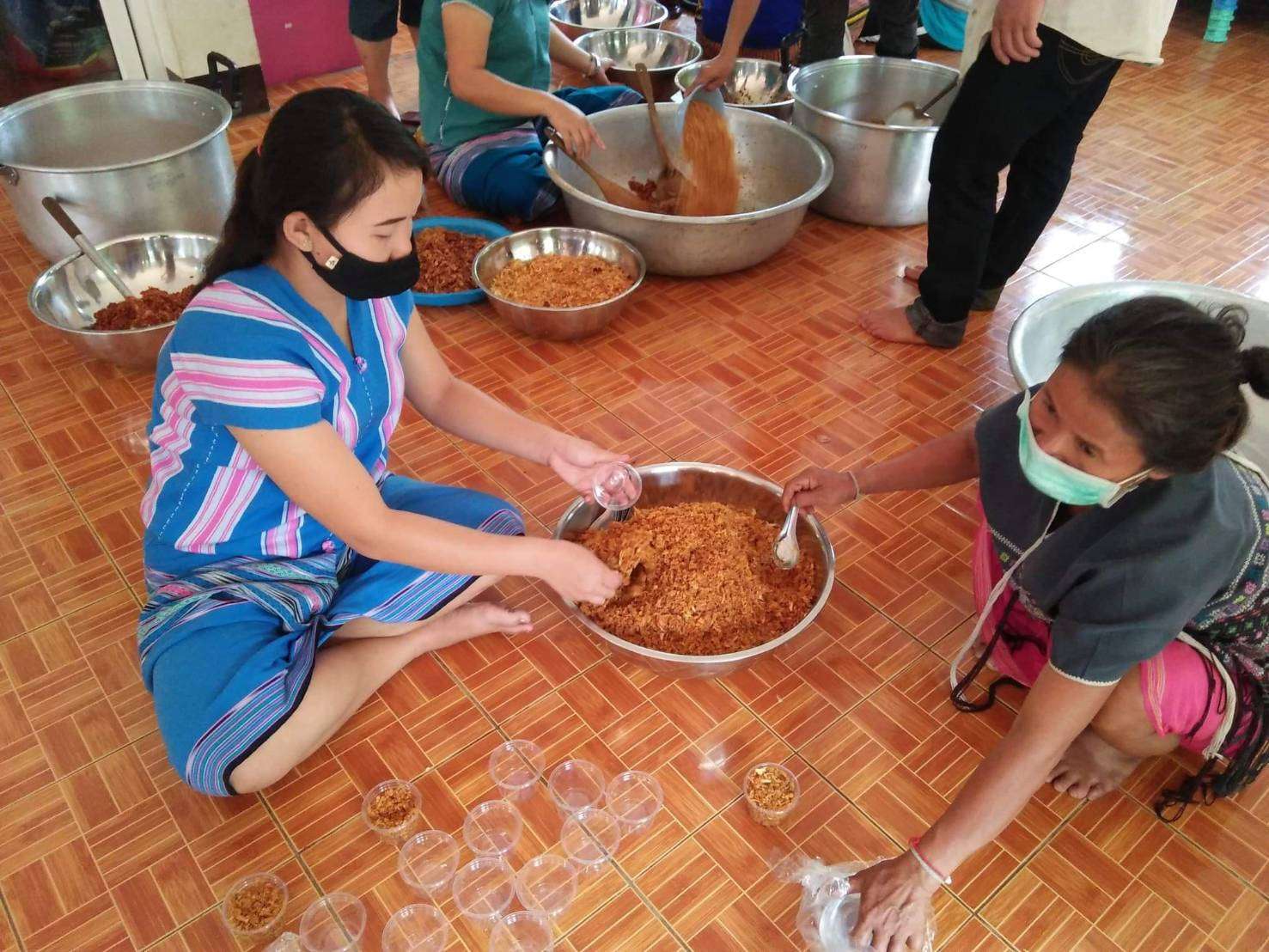 Youth and parents working together to craft flavorful galangal chili paste with salted fish.