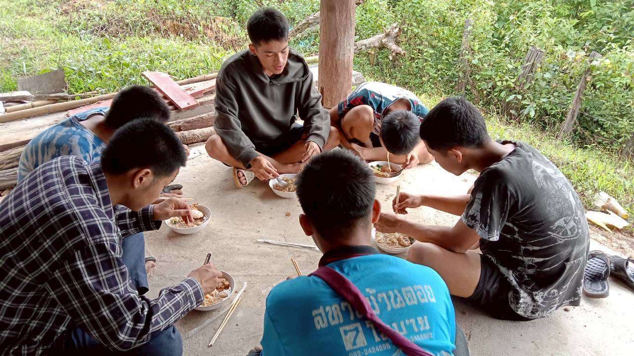 Children sitting and having a meal underneath the church building.