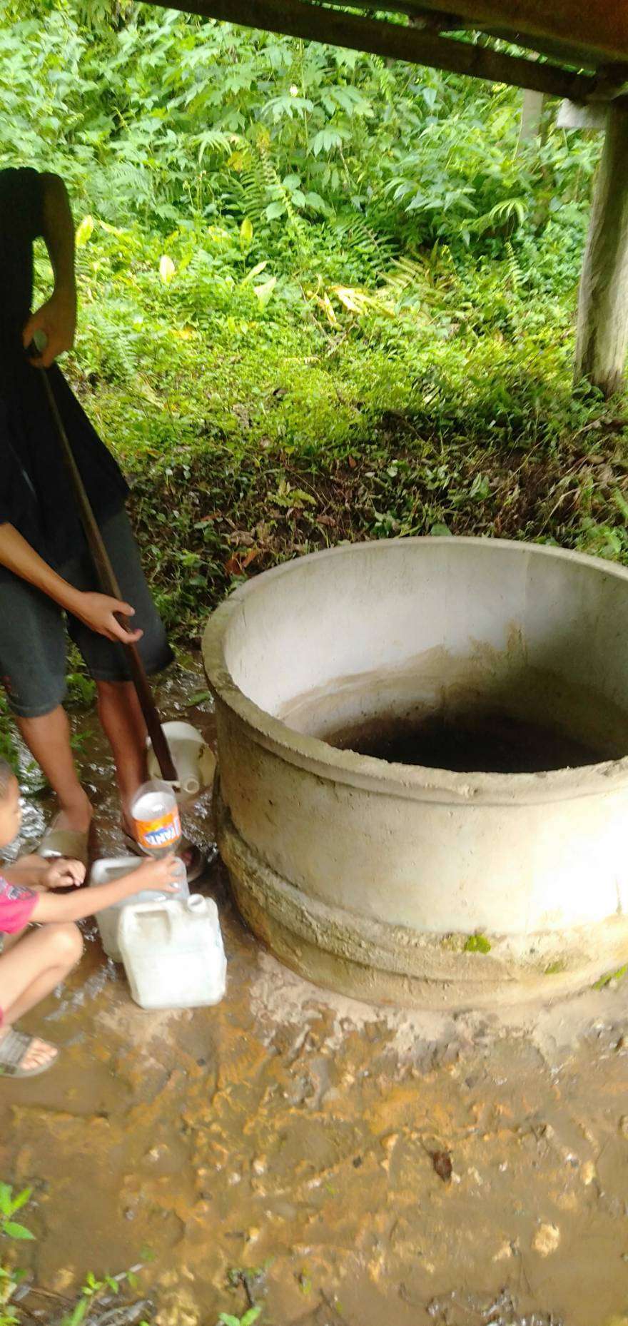 Children are scooping water from a community well.