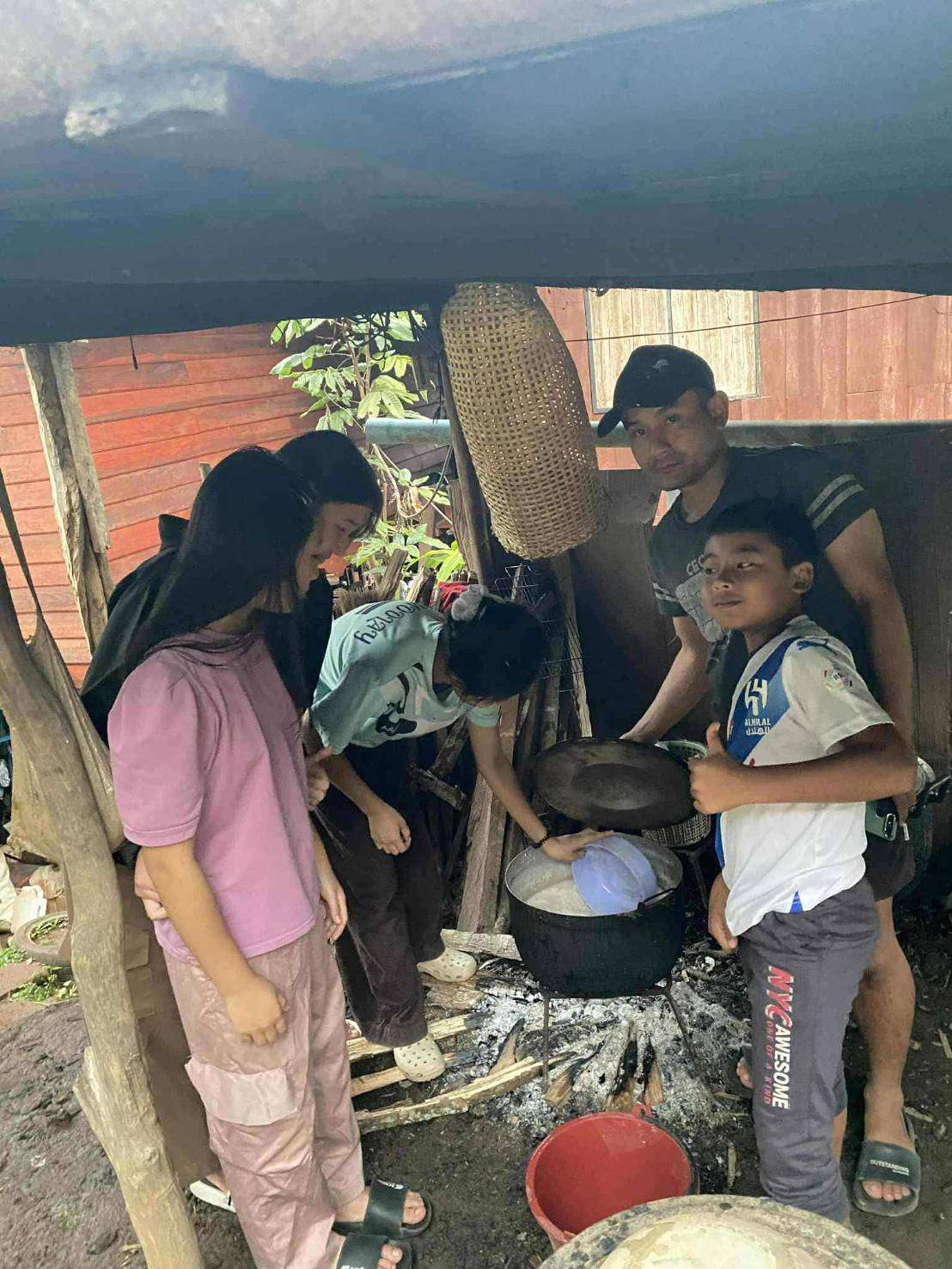 Children help boil food for the pigs for their meals
