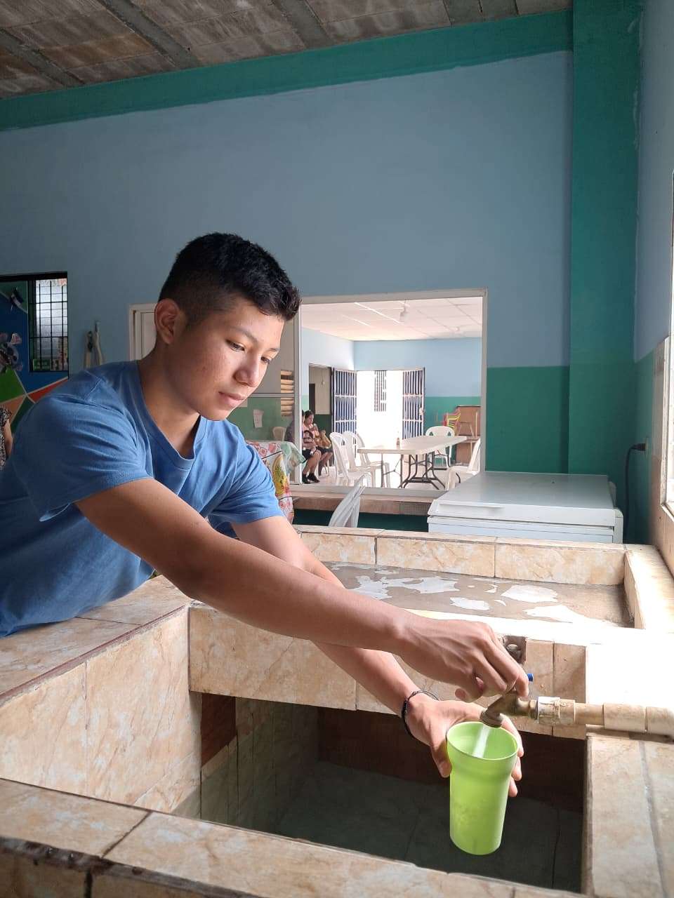Young man filling a glass with water for consumption