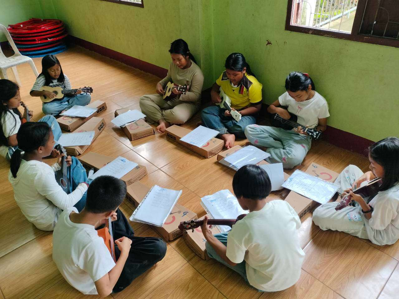 A group of young children are learning the ukulele with great dedication.