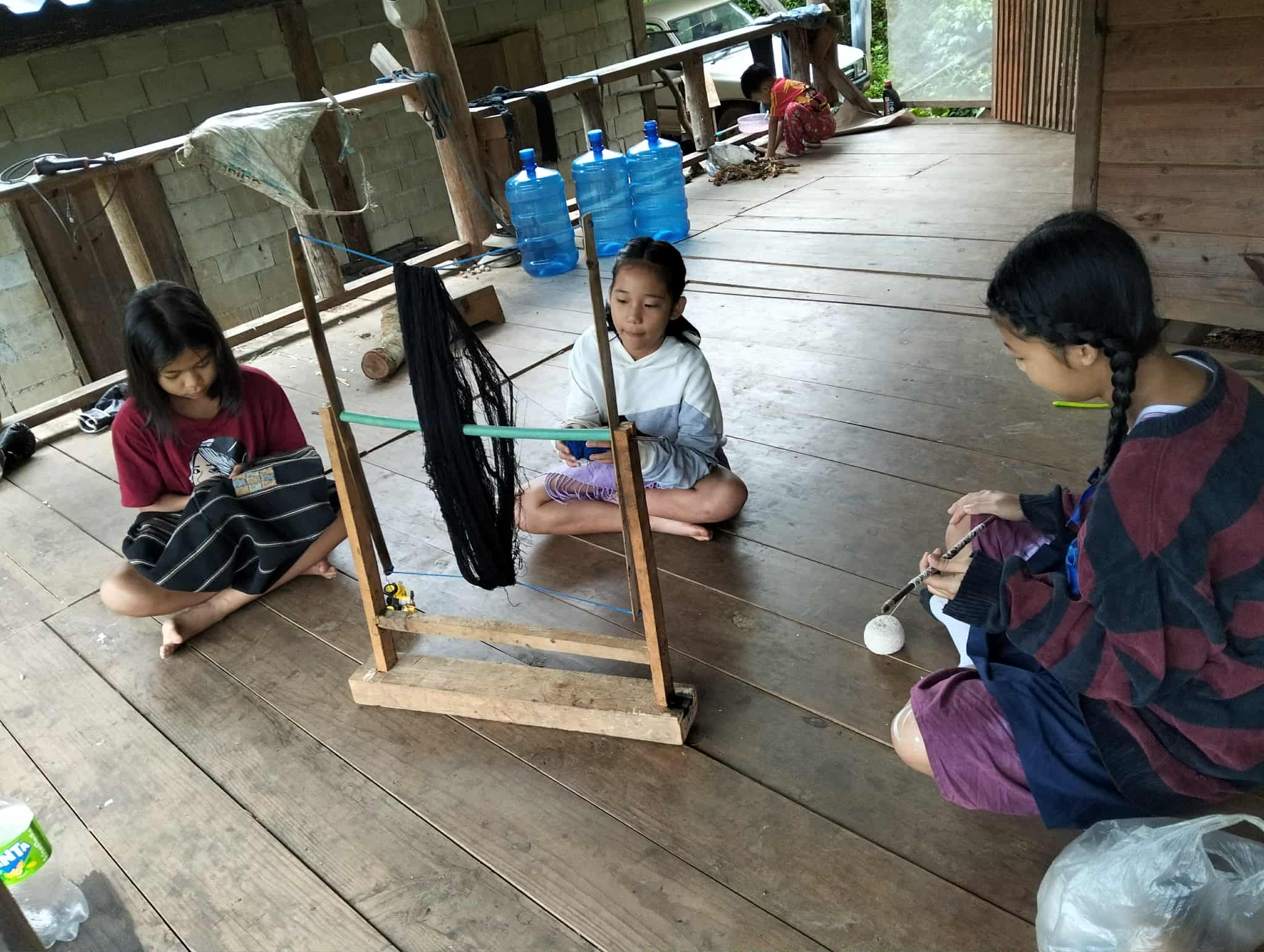 A girl spins cloth that will be woven into a piece for processing.