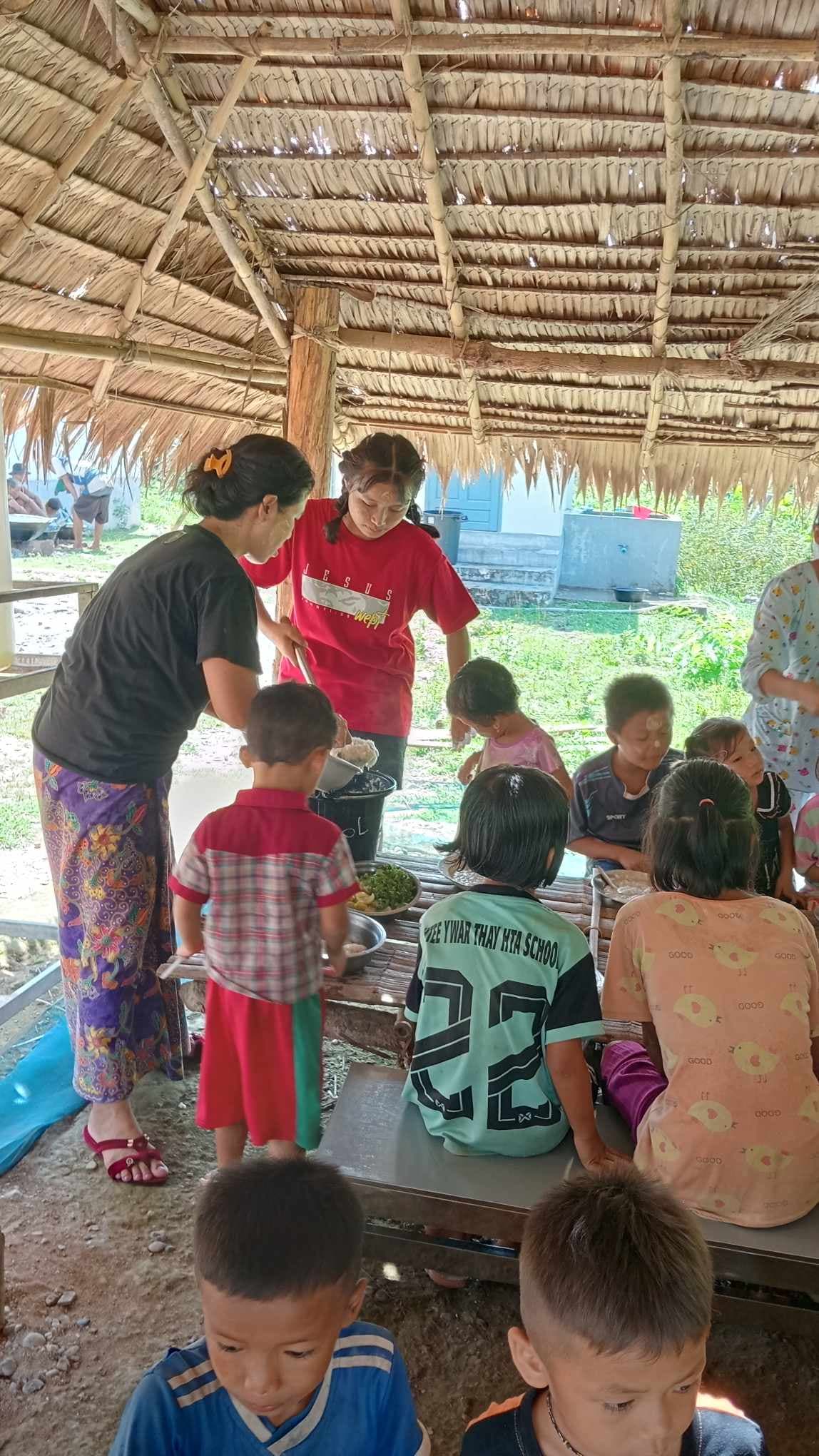 The teacher is cutting food for the children to eat.