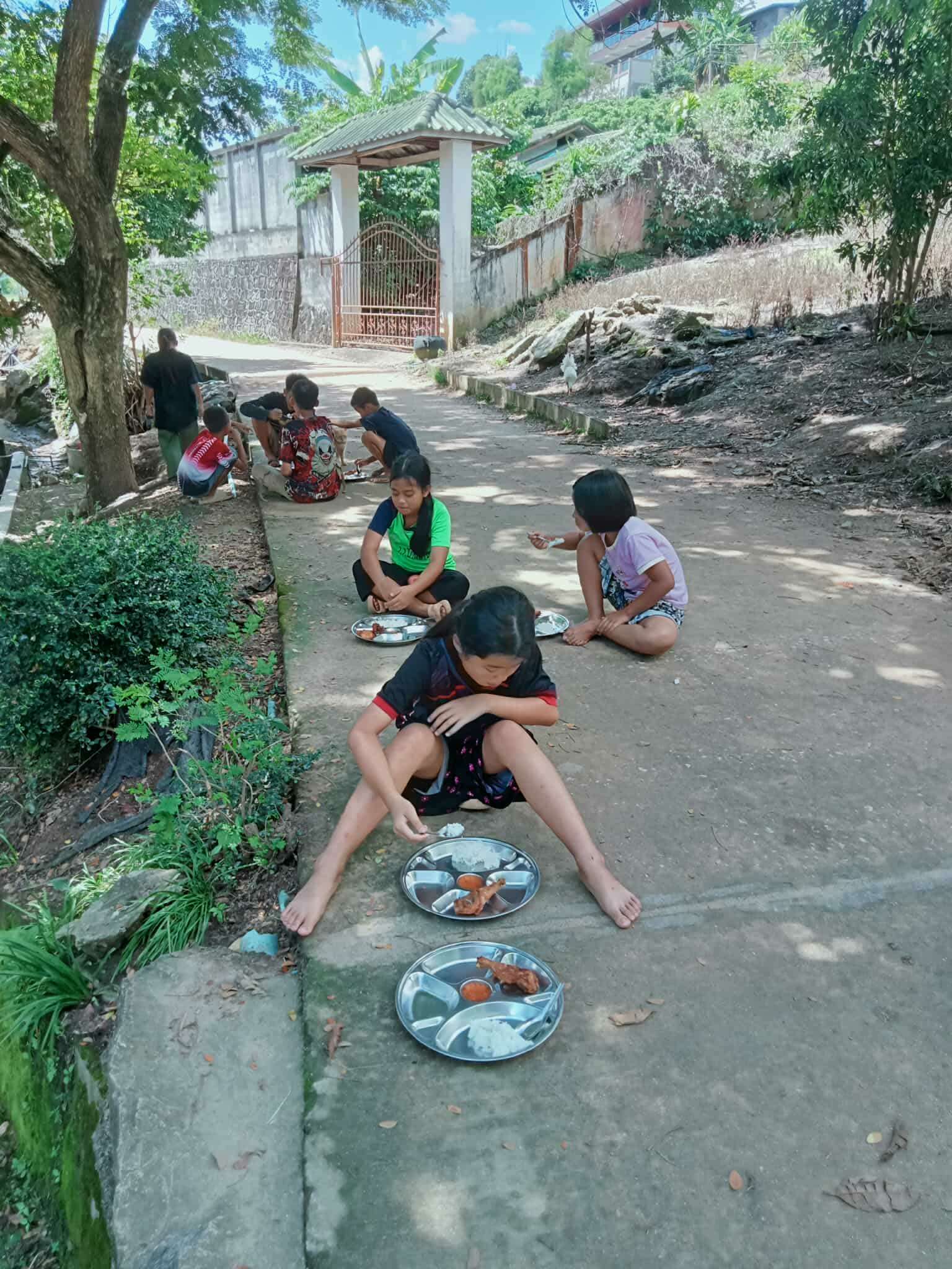 Under the shade of a tree, our children savor their meals