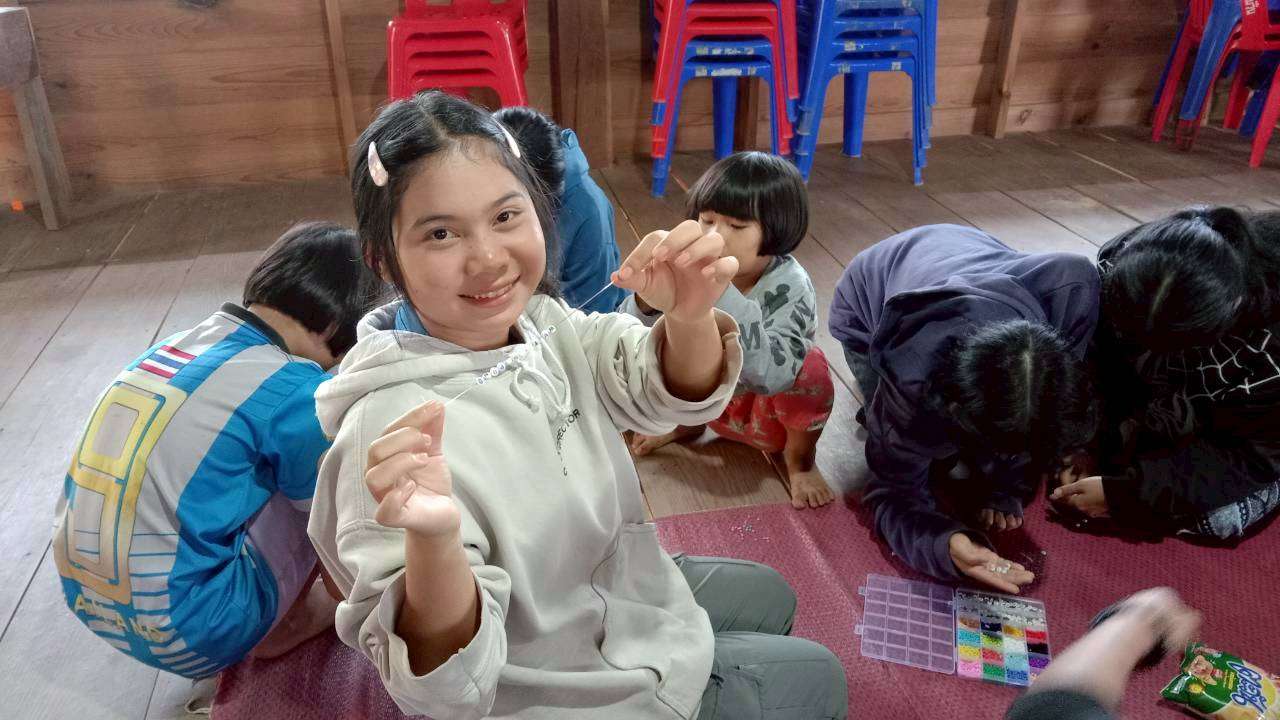 Children learning handicrafts by making bracelets after meals.